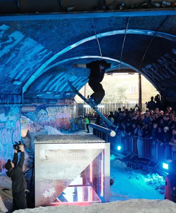 Peak Performance — skier mid-air over snow under the railway arch