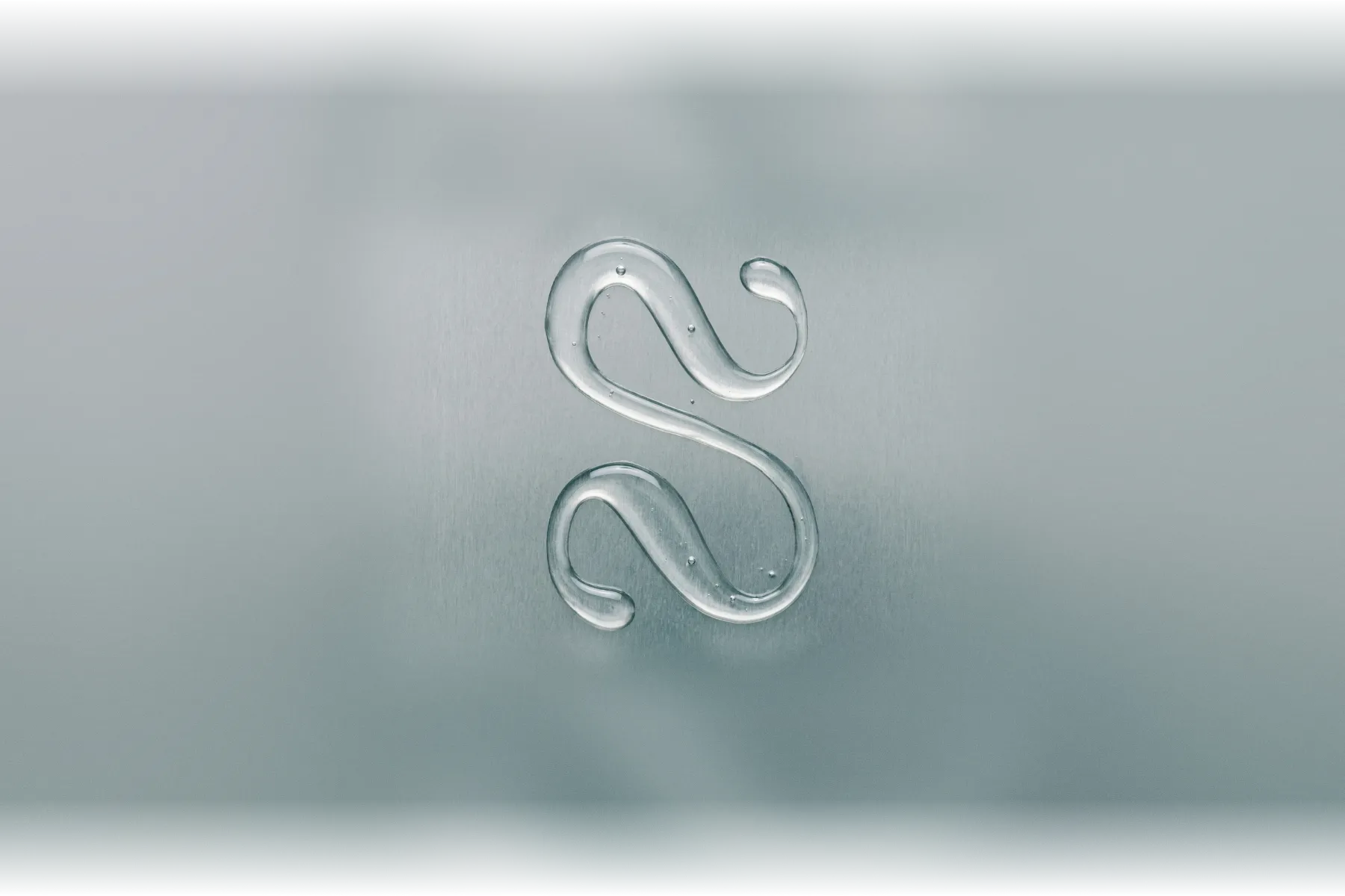The Solstice monogram drawn in clear water on brushed steel