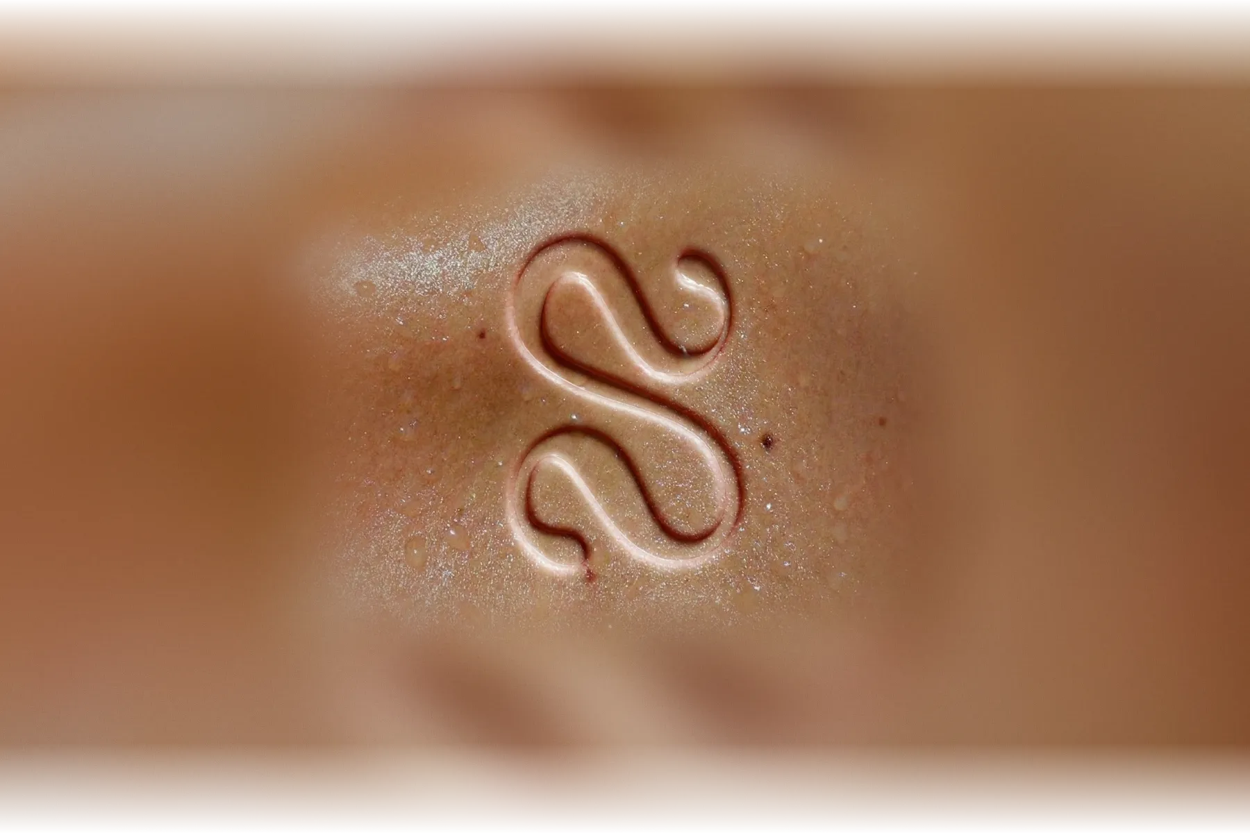 The Solstice monogram pressed into dewy skin