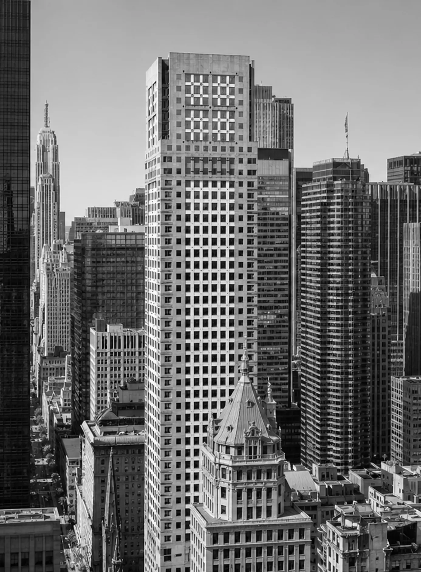 Black and white cityscape with tall buildings, focusing on a large grid-windowed skyscraper.