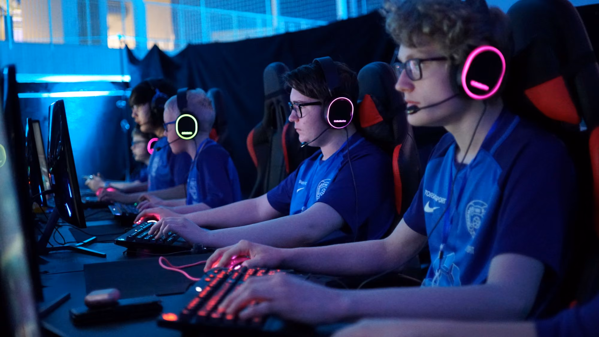 Ungdommer med headset og gamingutstyr konkurrerer i en esports-turnering.