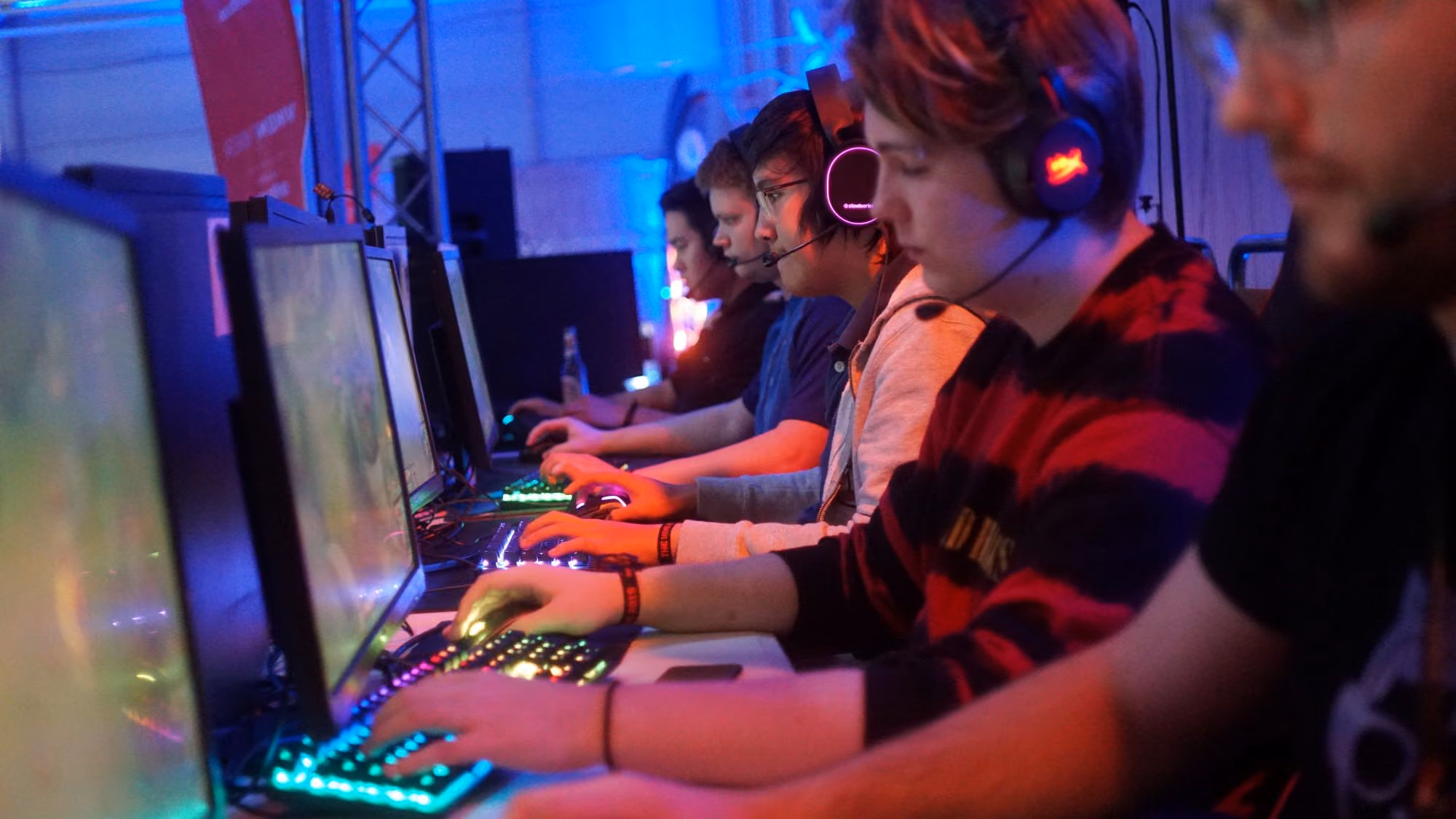 En gruppe unge personer med headset spiller PC-spill sammen på et LAN-party.