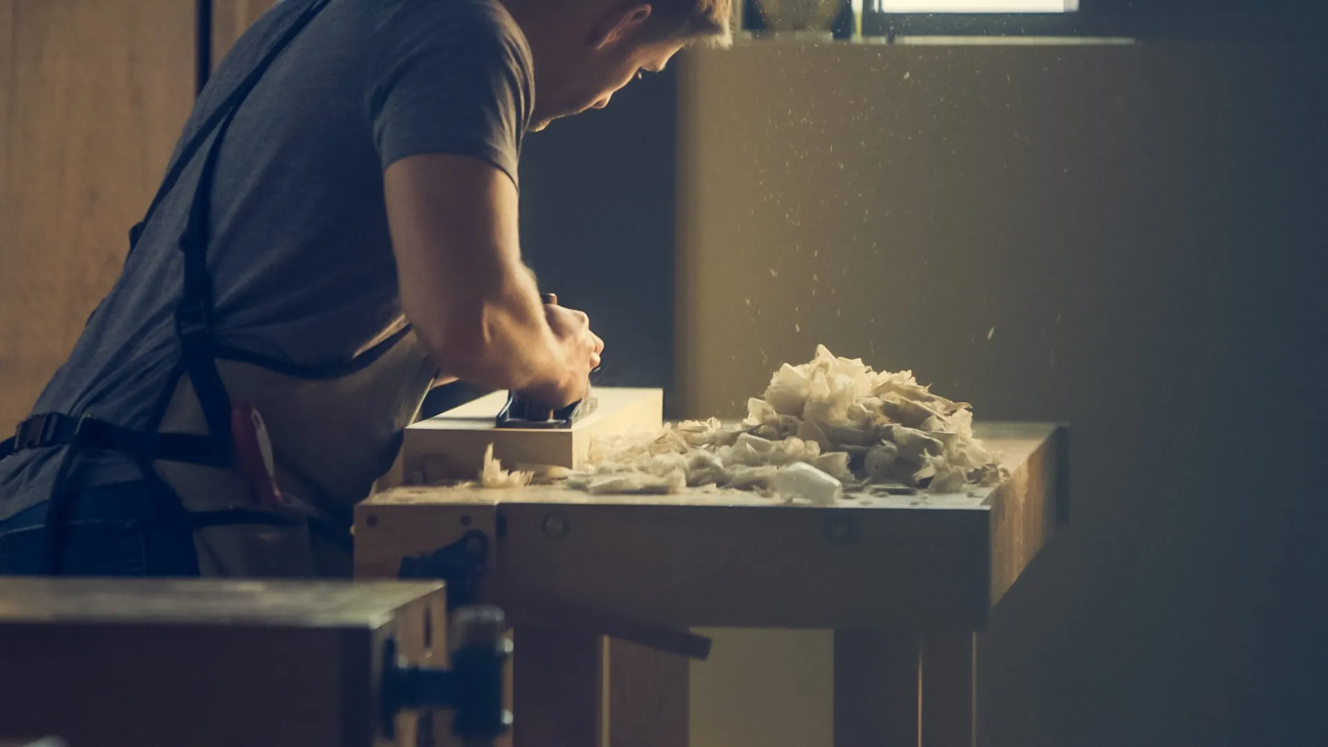 Handwerker bei der Holzbearbeitung in einer Werkstatt mit Holzspänen auf der Werkbank