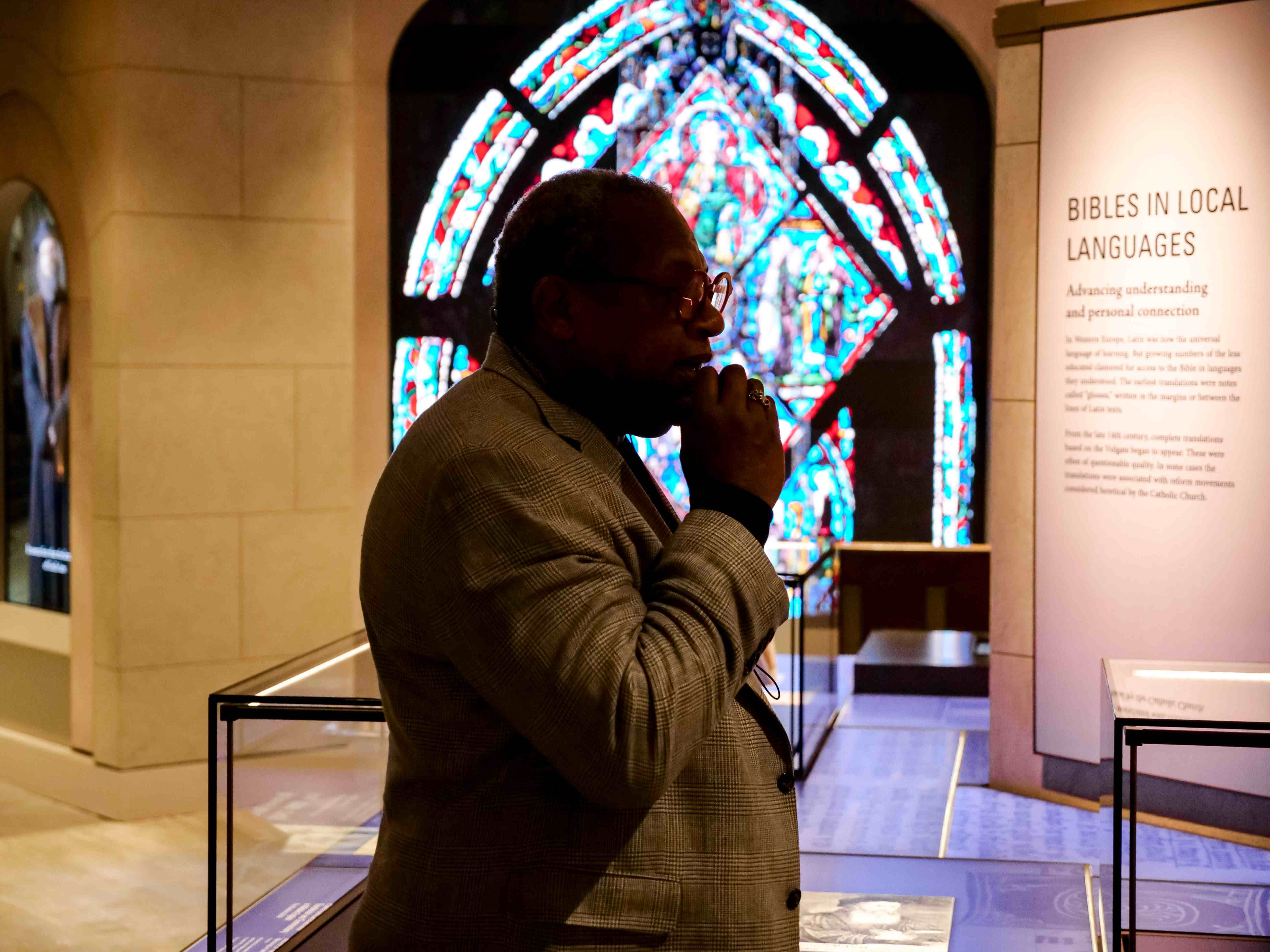 An Inspire guide teaches guests inside the Museum of the Bible in Washington, D.C., with a stained-glass display in the background.
