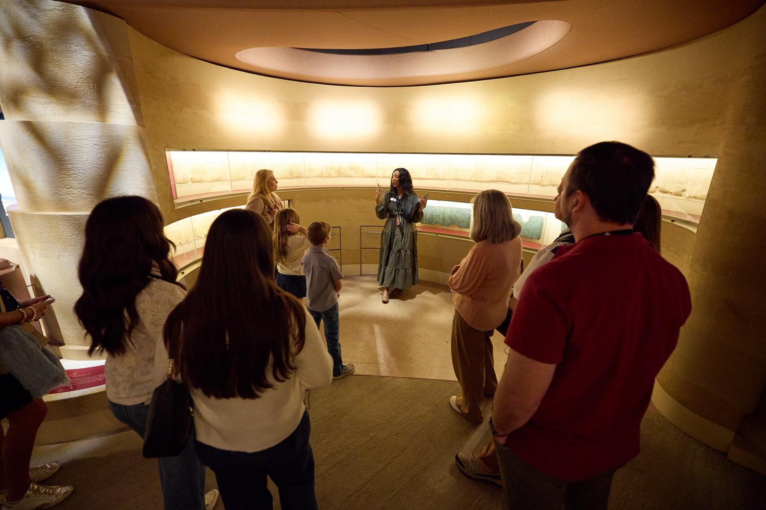 An Inspire guide explains the significance of the Dead Sea Scrolls and the Great Isaiah Scroll facsimile to guests inside the Museum of the Bible.