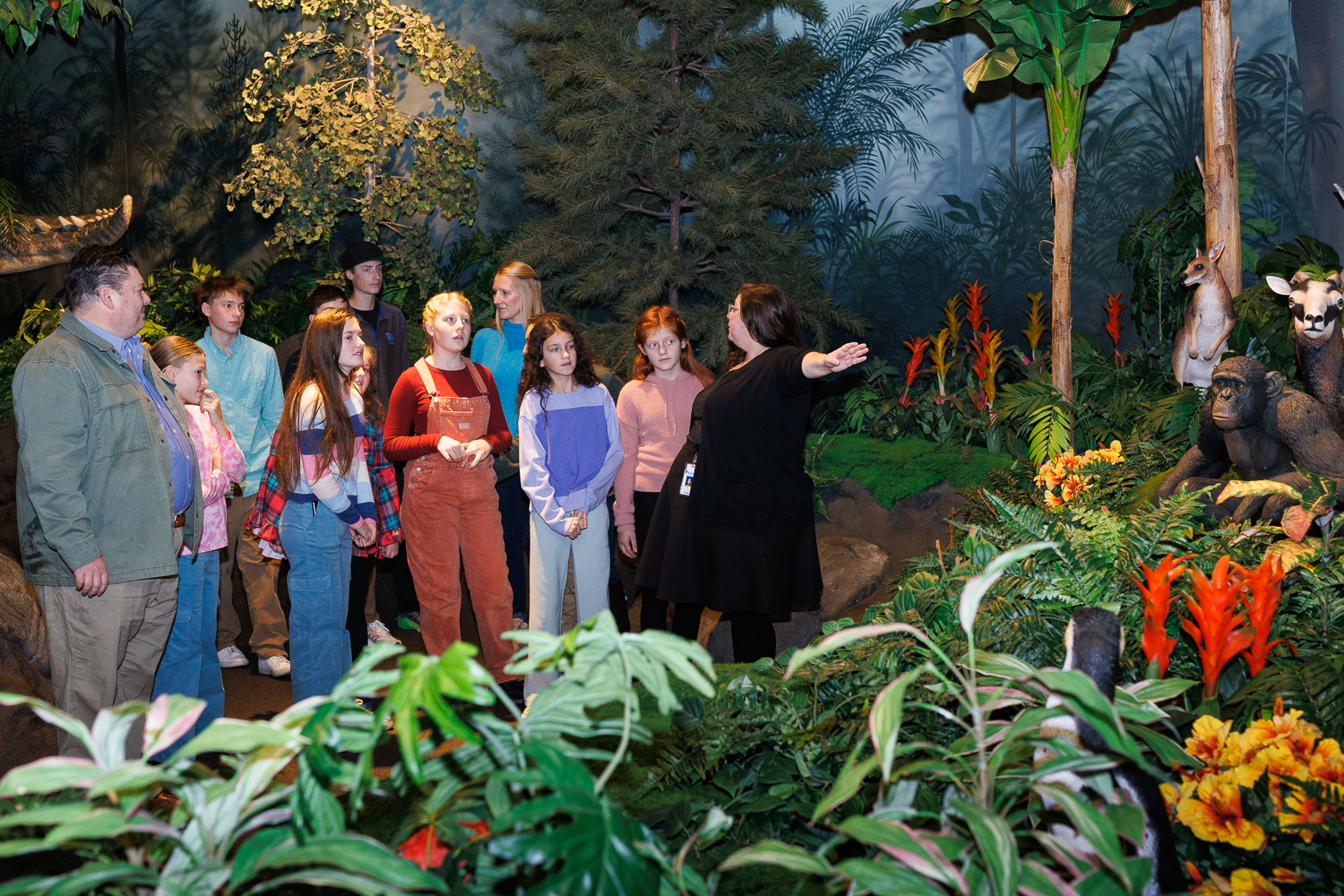 An Inspire guide explains God's creation to guests in the Creation Museum's Garden of Eden exhibit, surrounded by lifelike animals and lush vegetation.