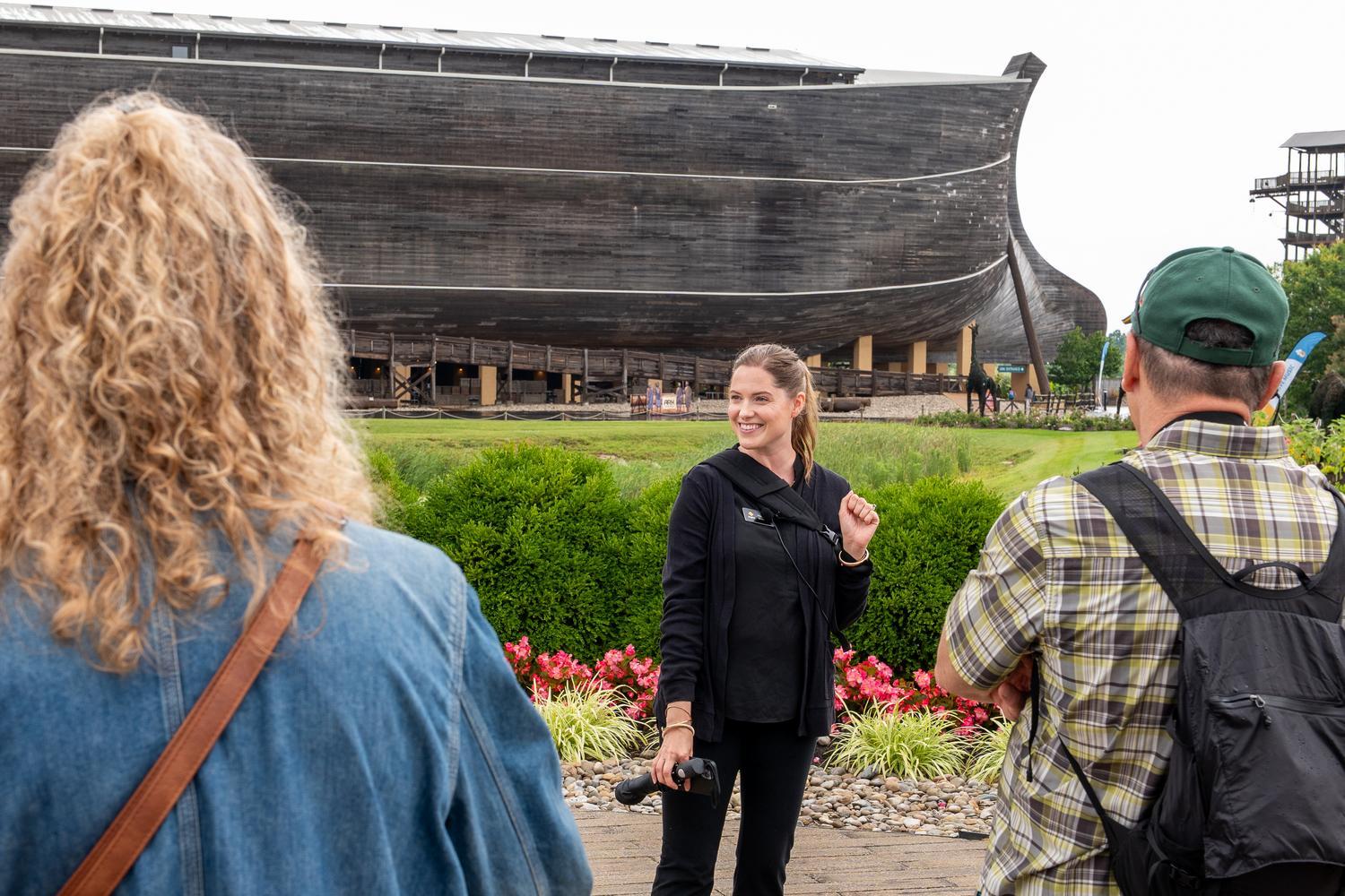 An Inspire guide welcomes guests outside the Ark Encounter, introducing the life-size Noah's Ark before a guided tour.