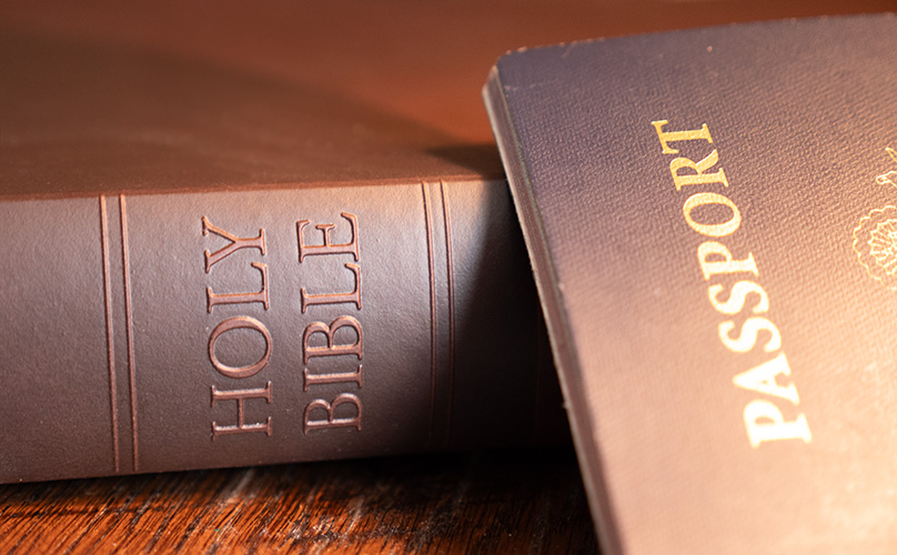 A Holy Bible and passport resting on a wooden table, representing Inspire's Christ-centered travel experiences rooted in God's Word.