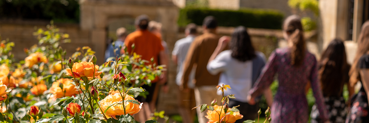 Guests walk through the gardens of Yarnton Manor near Oxford, England, with blooming roses in the foreground.