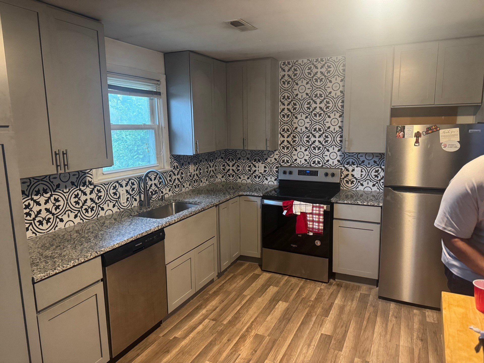 Completed kitchen remodel with grey shaker cabinets, granite countertops and a patterned tile backsplash