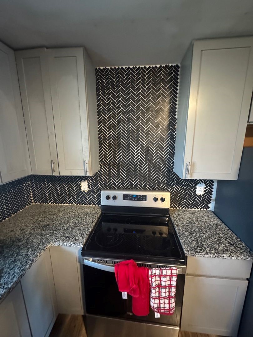 Kitchen range wall before remodeling, with the original dark herringbone tile backsplash