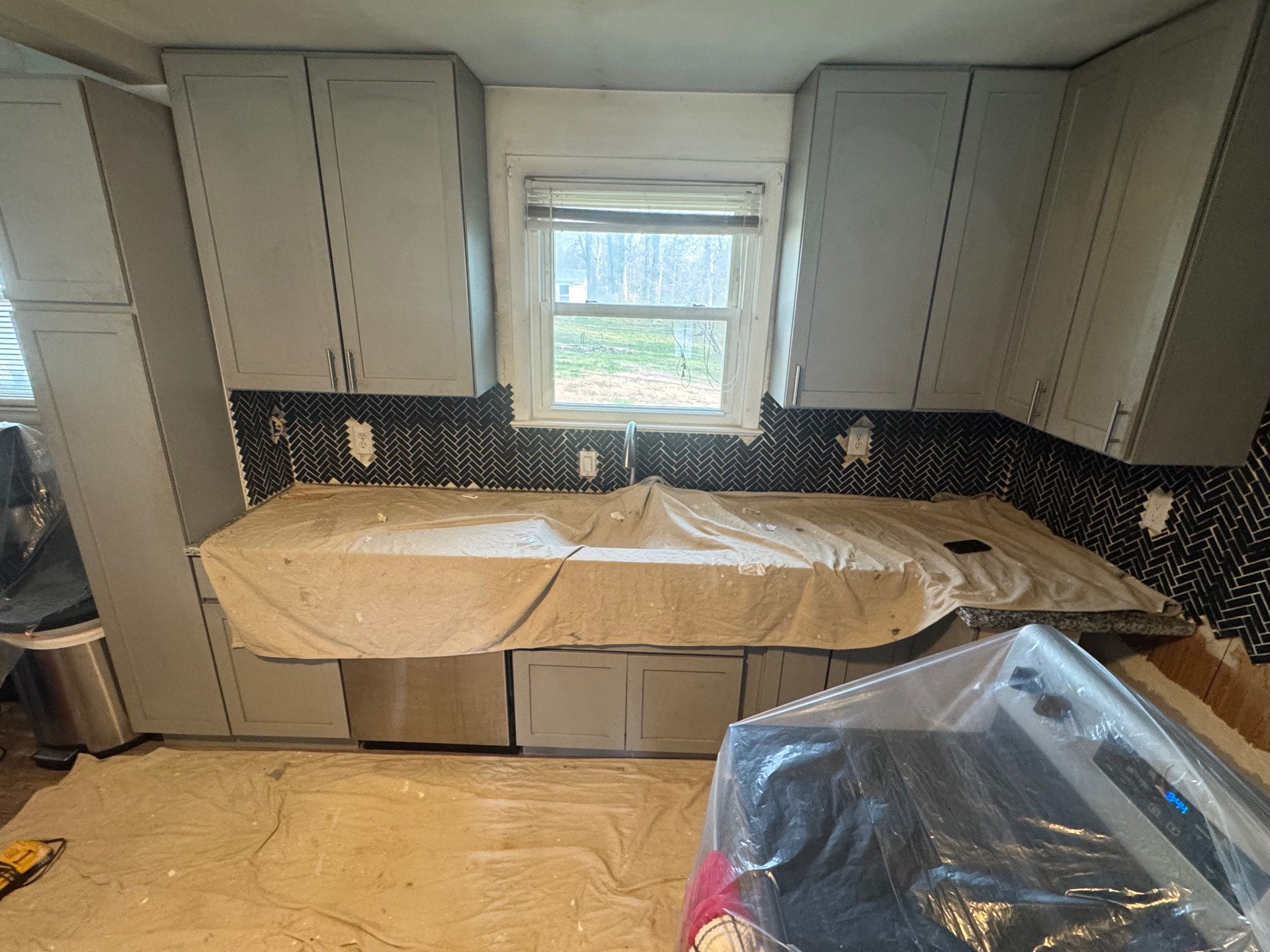 Kitchen remodel in progress, with countertops and floors protected by drop cloths