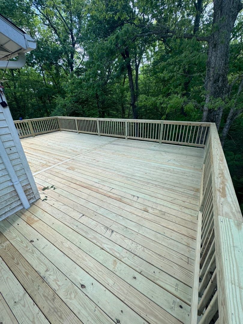 Newly built pressure-treated deck with railings, overlooking woodland