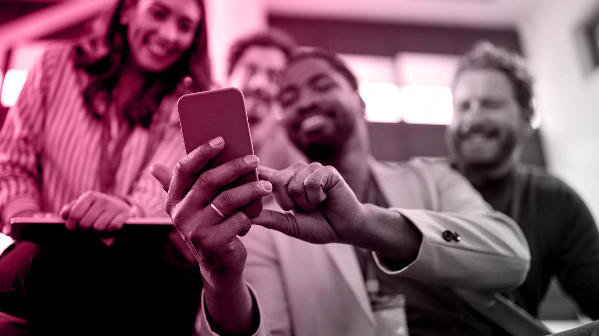 Colleagues at a conference smiling at a smartphone, representing Meta Advantage+ campaigns