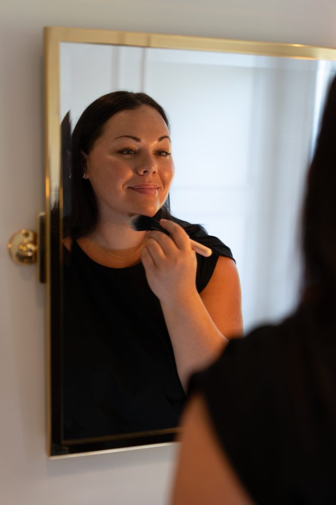 Smiling woman applying makeup.