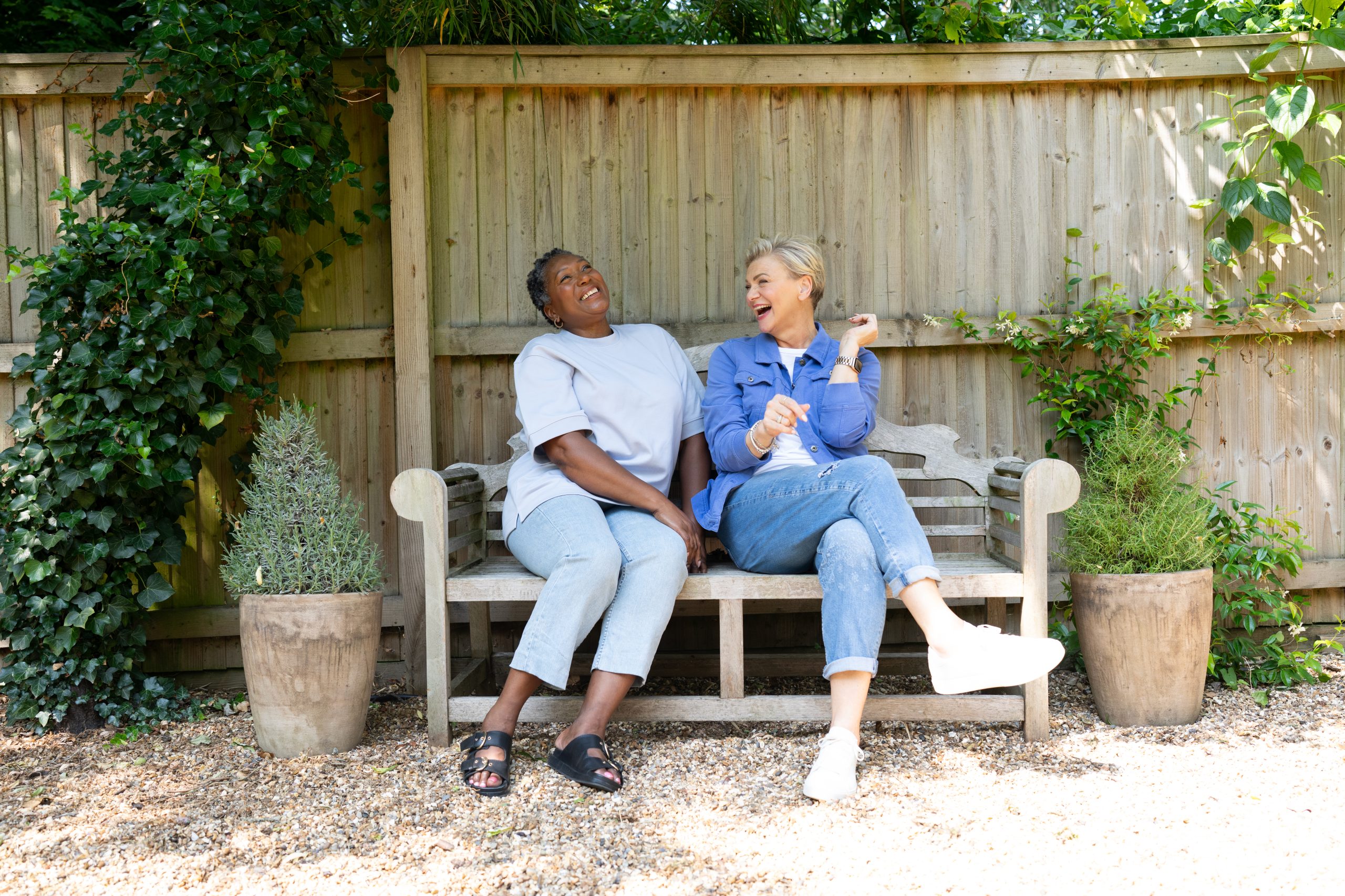 Two women sat on a bench laughing.