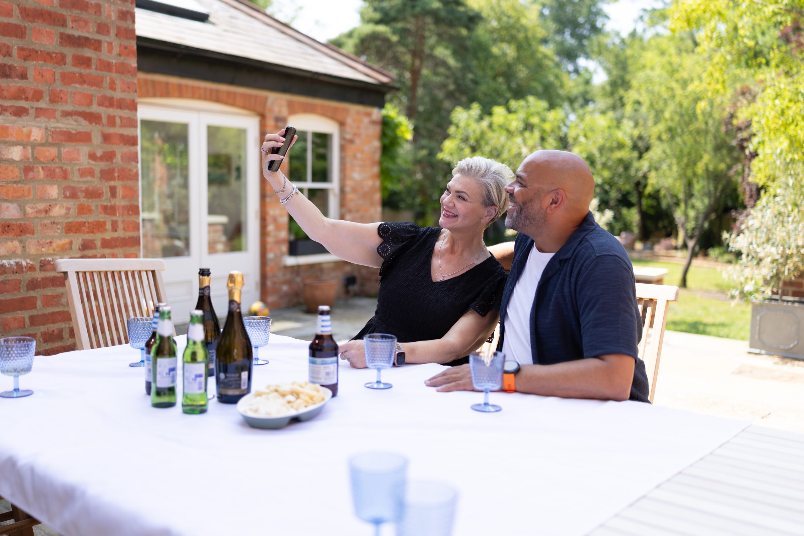 Couple taking a picture outside around a table.