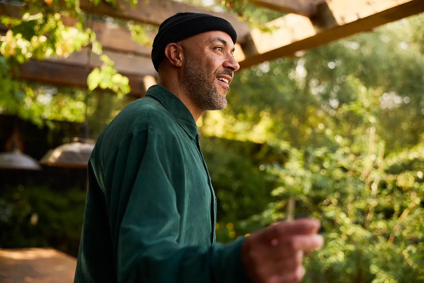 A man in a beanie and green shirt smiling outdoors