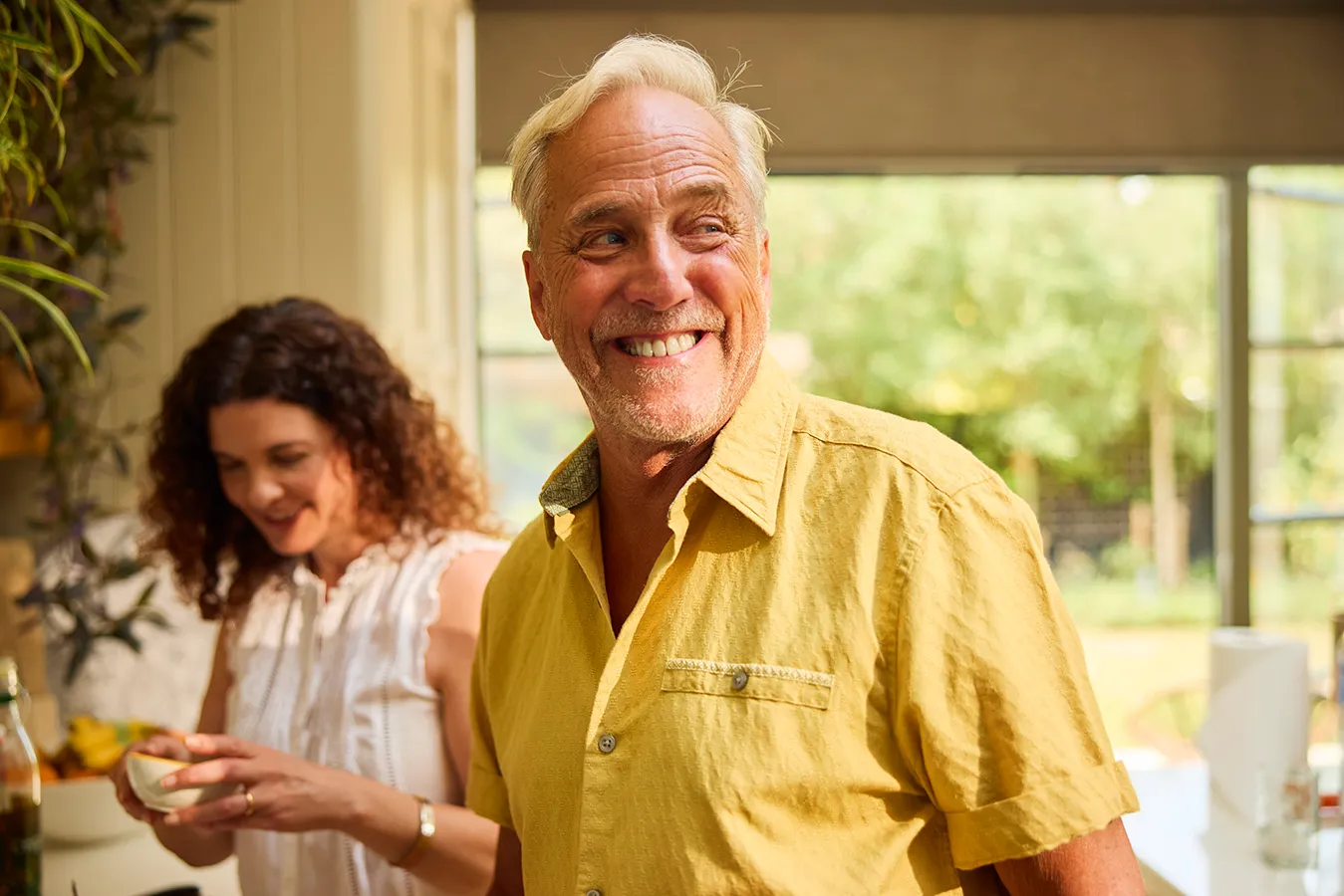 A man in a blue shirt smiling by a window