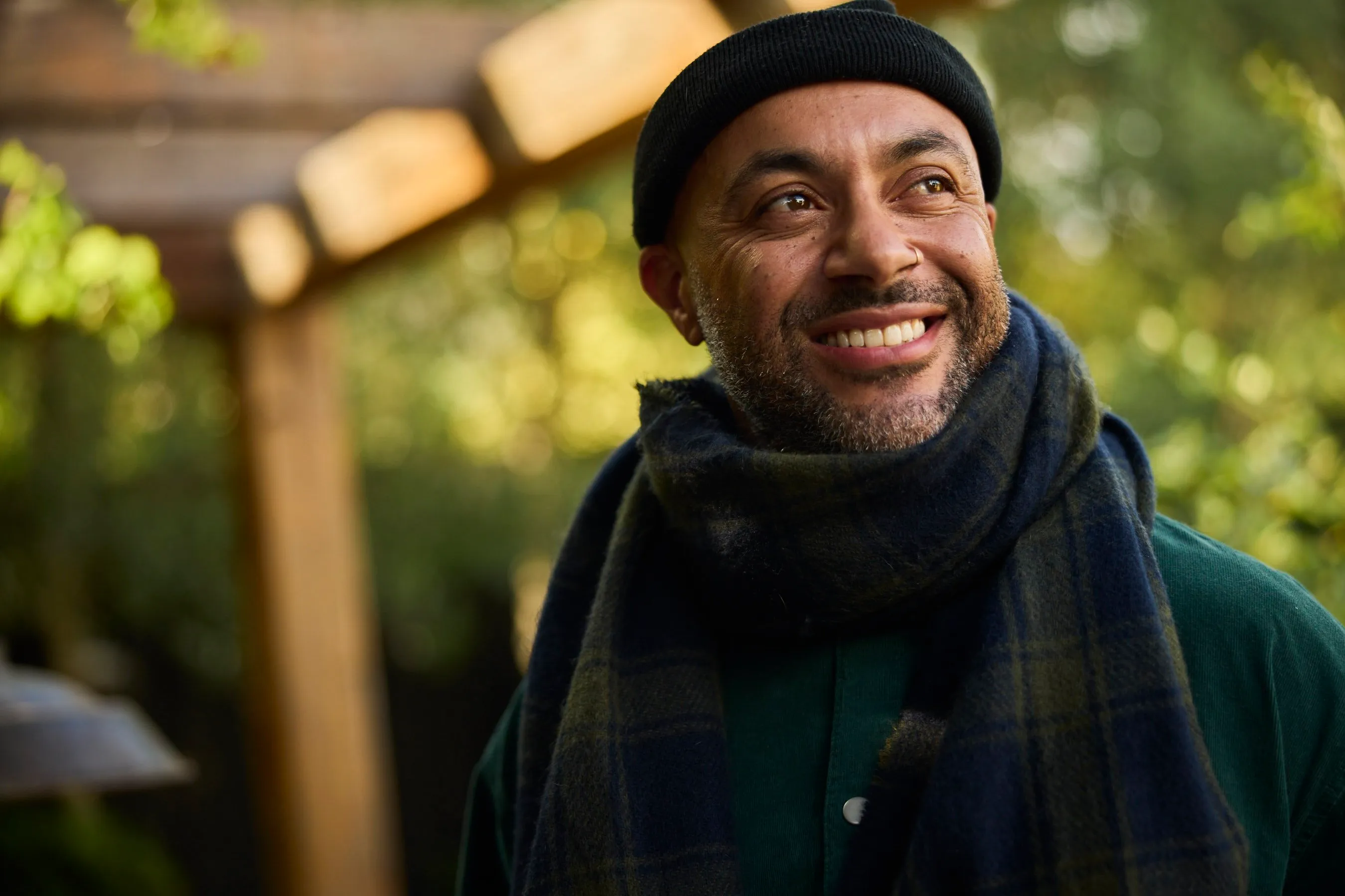 A man in a beanie and scarf smiling outdoors