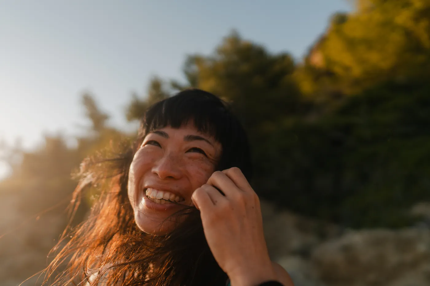 A woman laughing outdoors in evening light