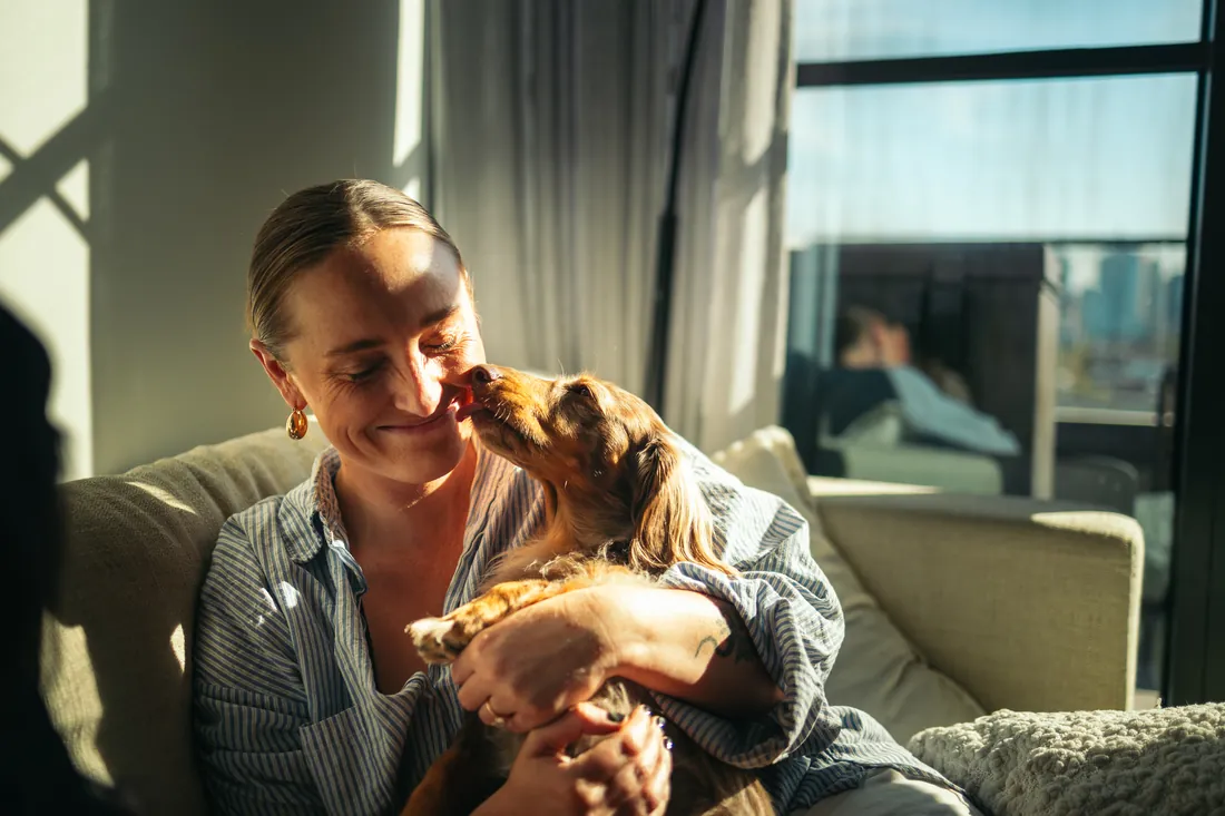 A woman sitting on a sofa with her dog