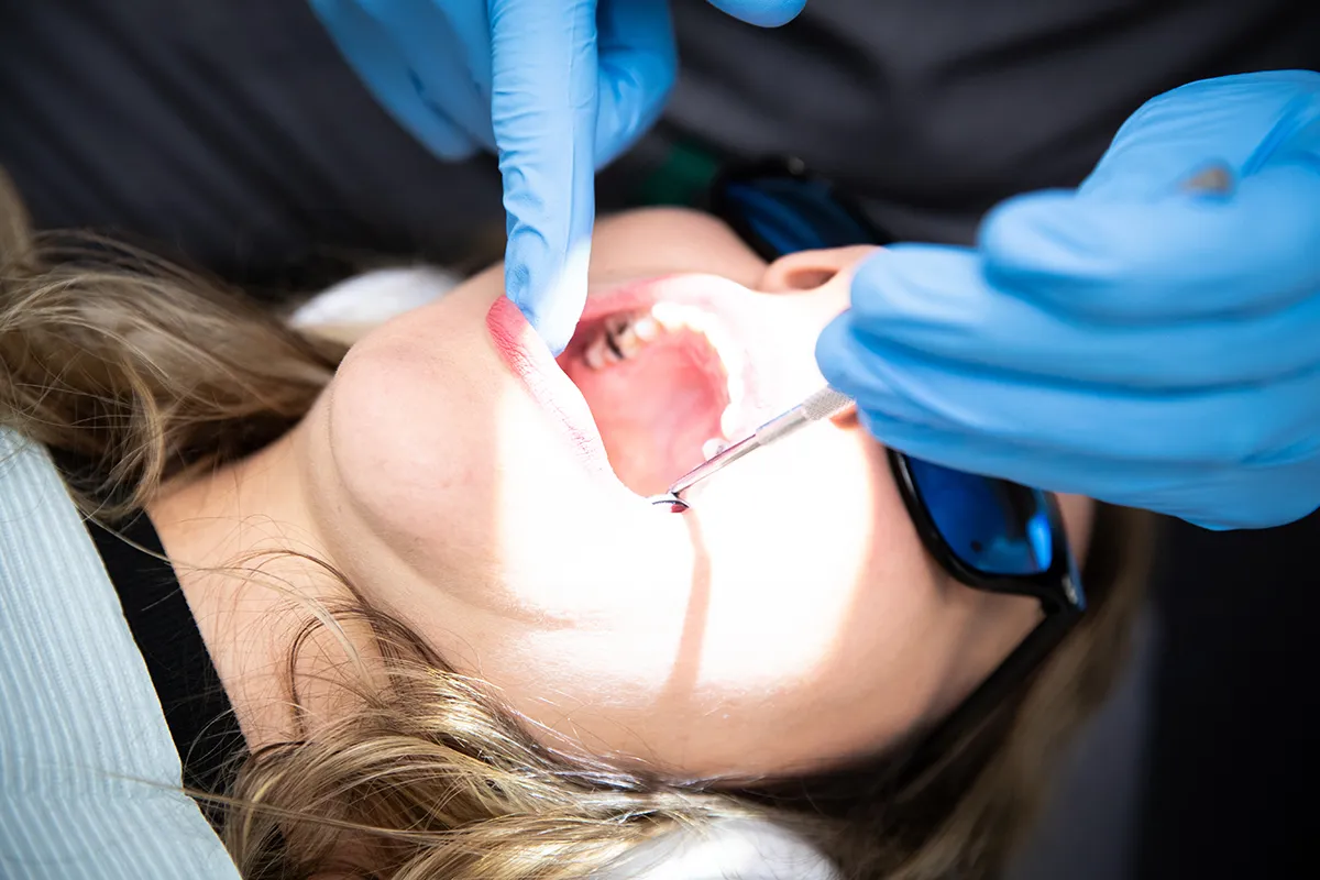Smiling and holding up her clear aligners
