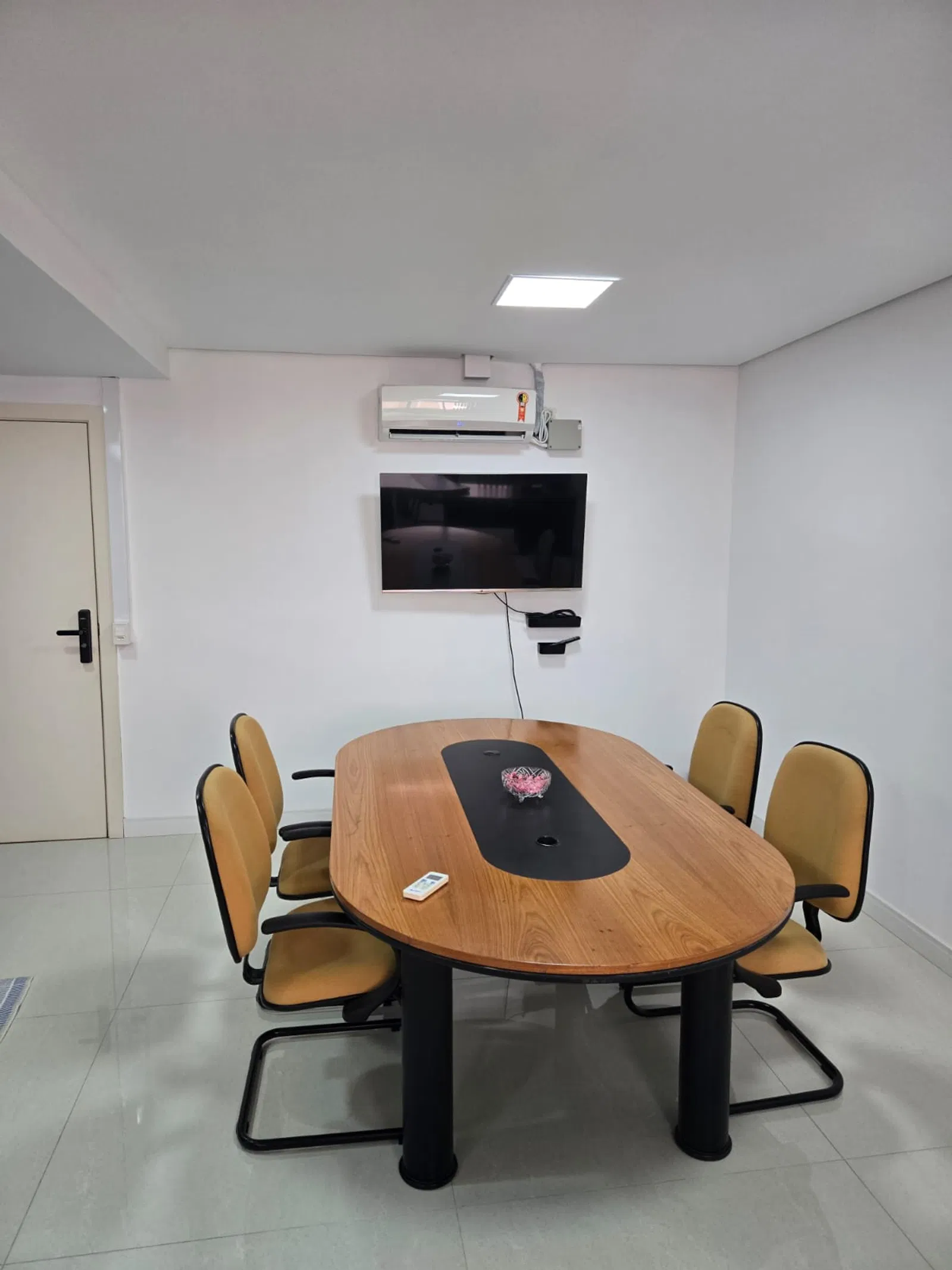 Sala de reunião moderna com mesa de madeira e equipamentos para apresentações
