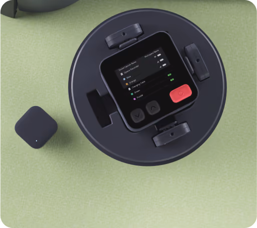 Top view of a black Nomono device with a screen displaying audio settings on a green surface.