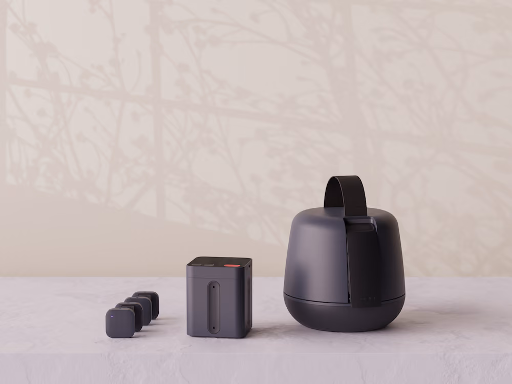 Modern dark grey portable speaker set with square and round shapes on a stone surface.