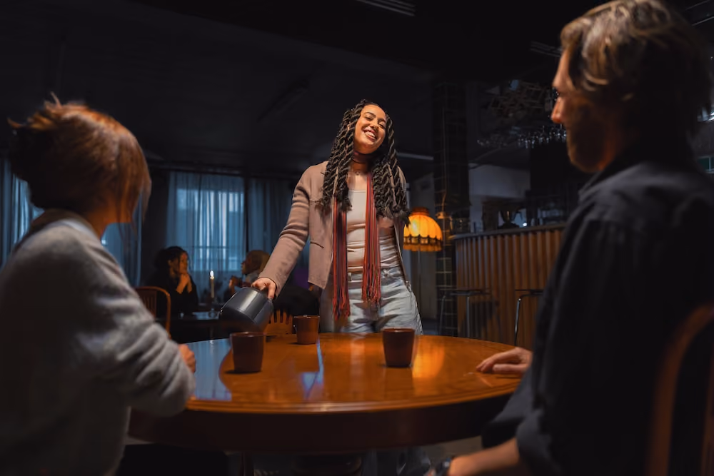Smiling woman with the Nomono Sound Capsules around a table with two other people.