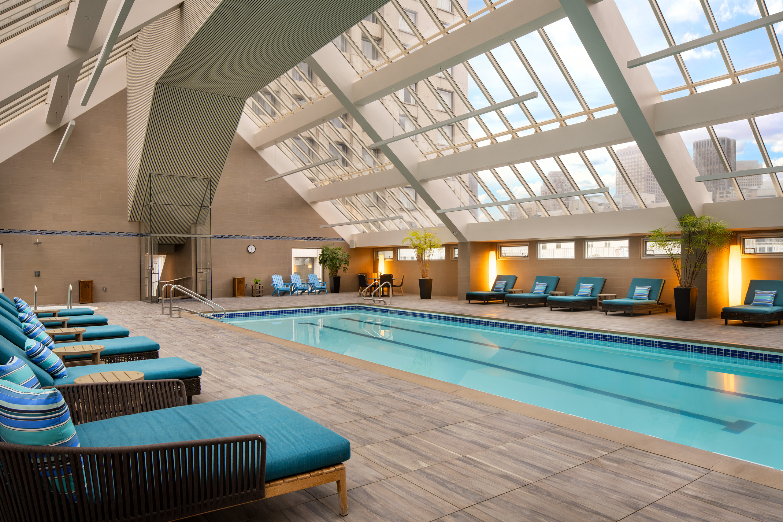 Indoor swimming pool with lounge chairs and skylight.