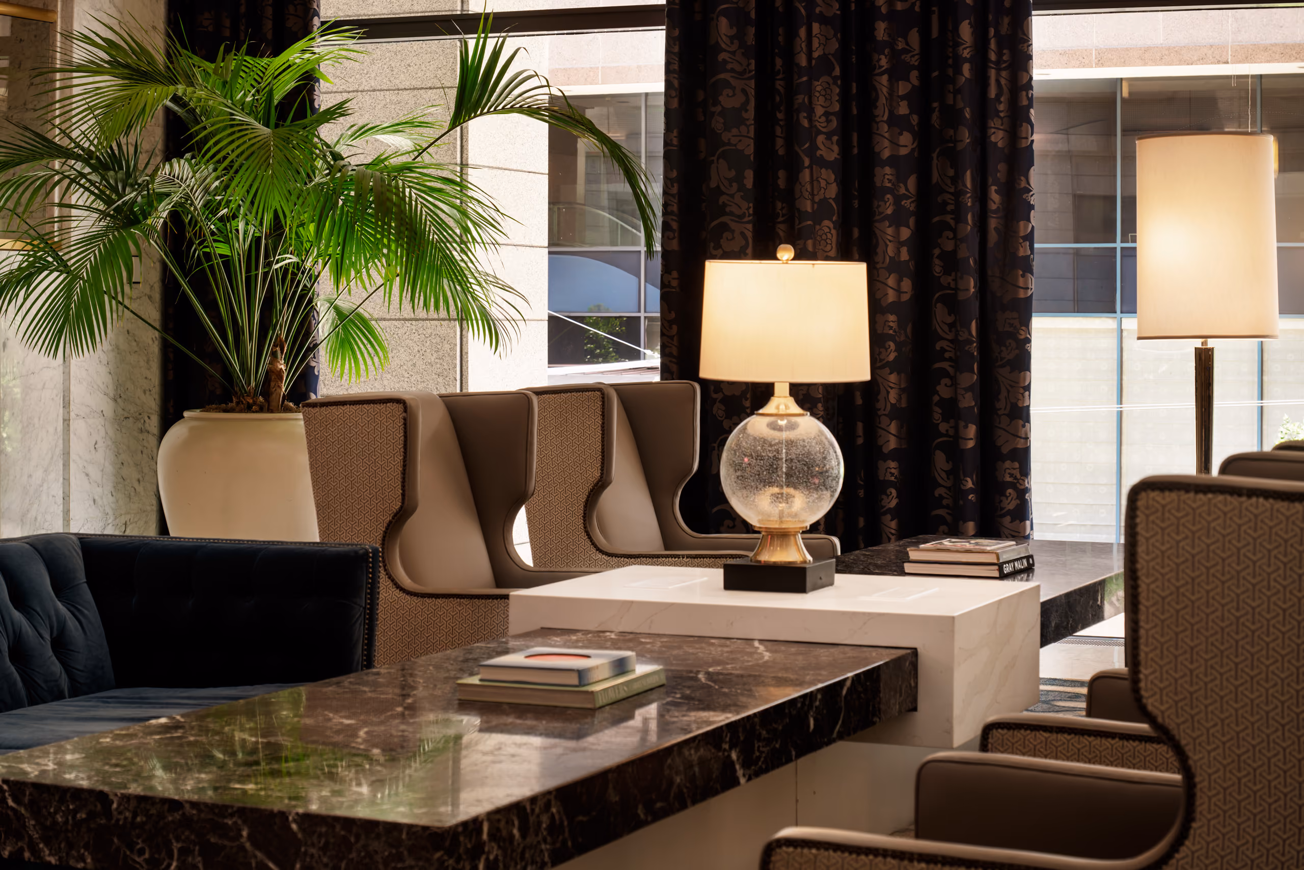 Hotel lobby seating with marble tables and plants.