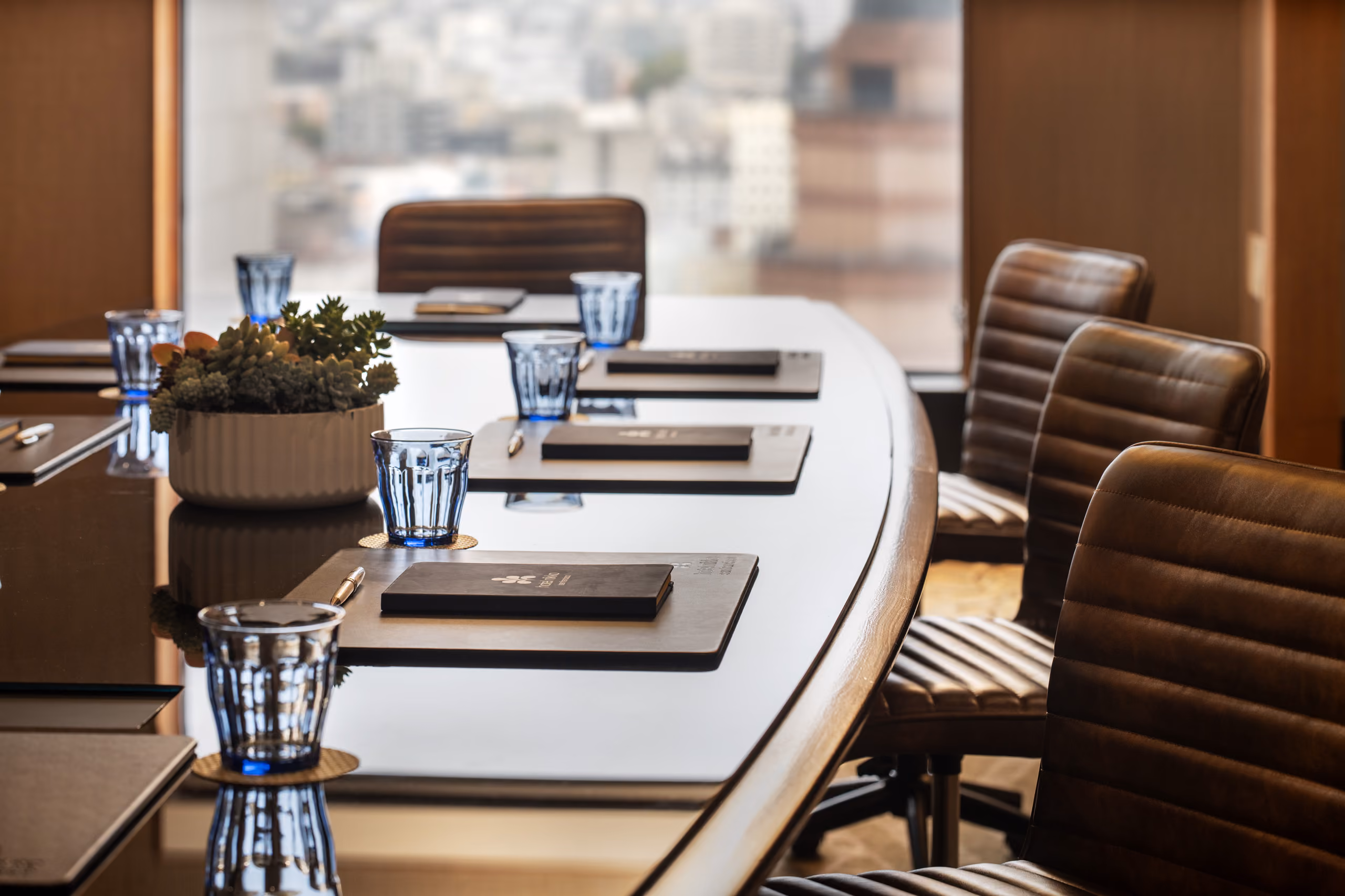 Boardroom table with notebooks, blue glasses, and succulent.