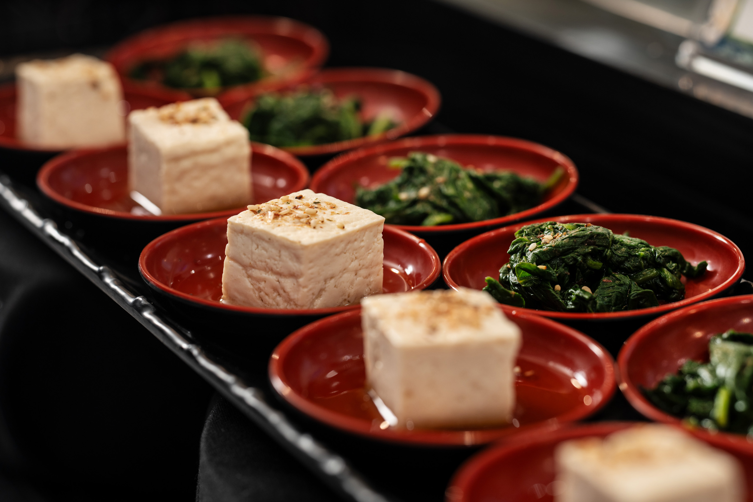 Tofu and seasoned spinach in individual serving bowls.