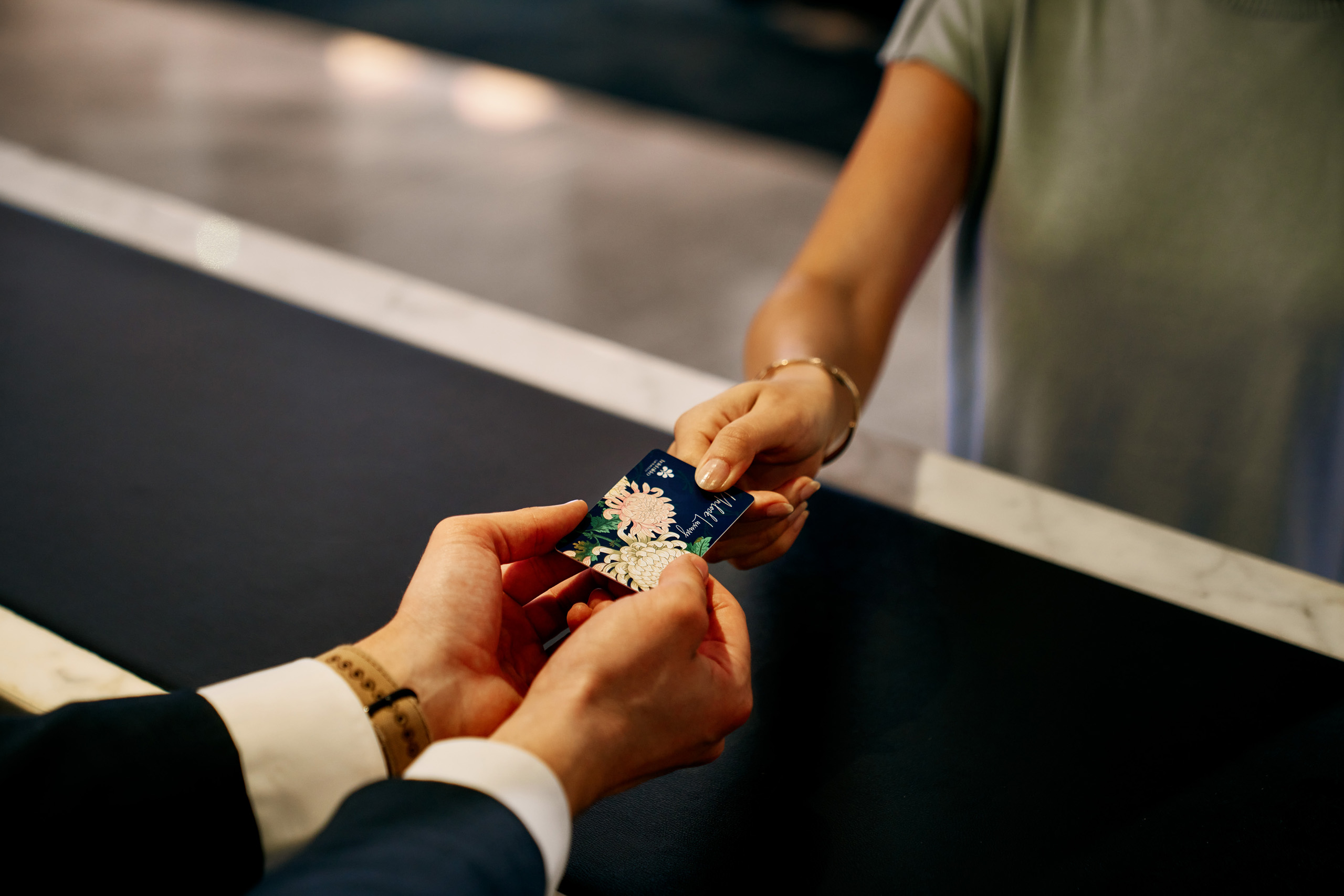 Close-up of hotel key card exchange at reception.