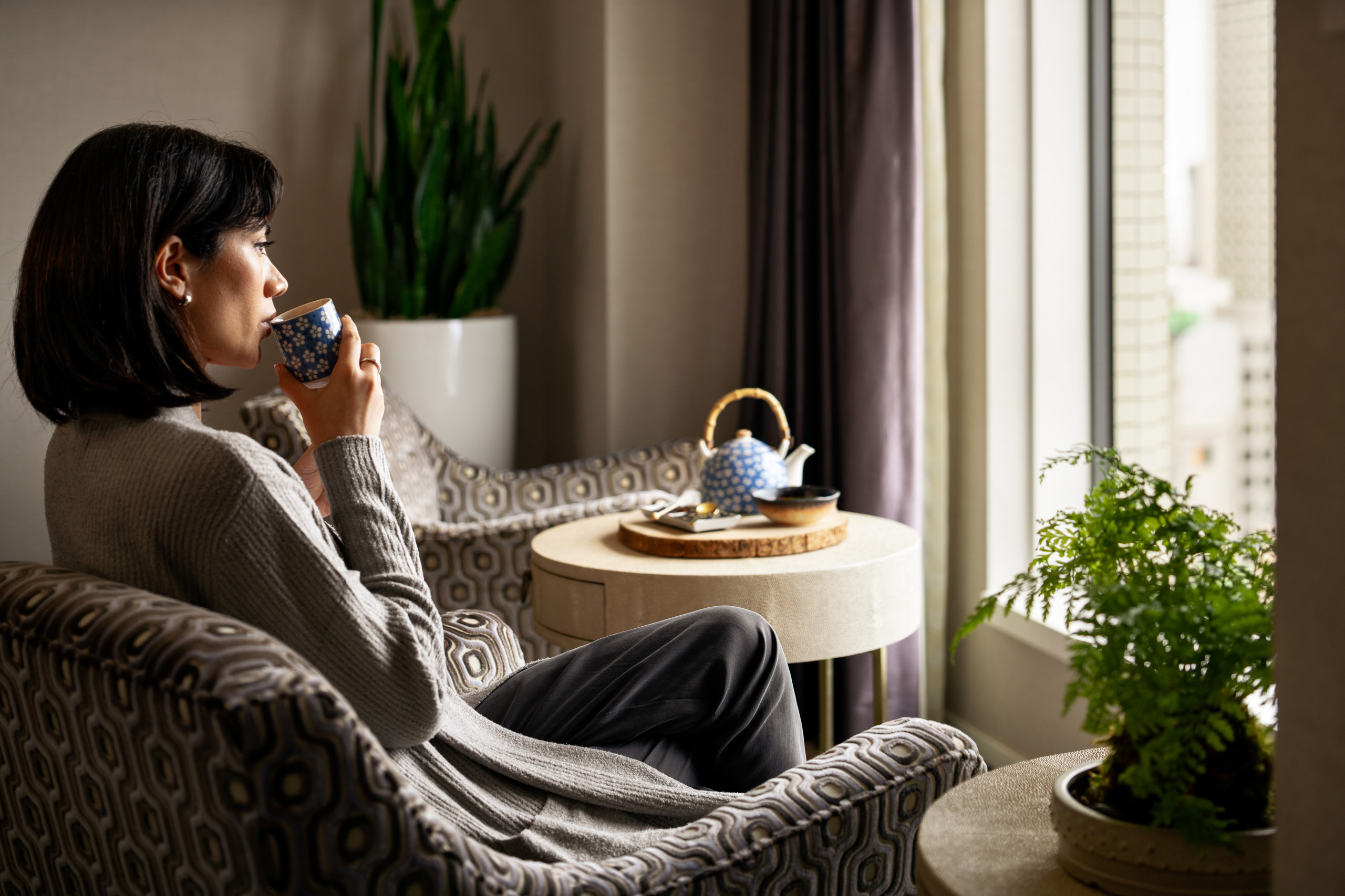 Guest enjoying tea beside hotel window.