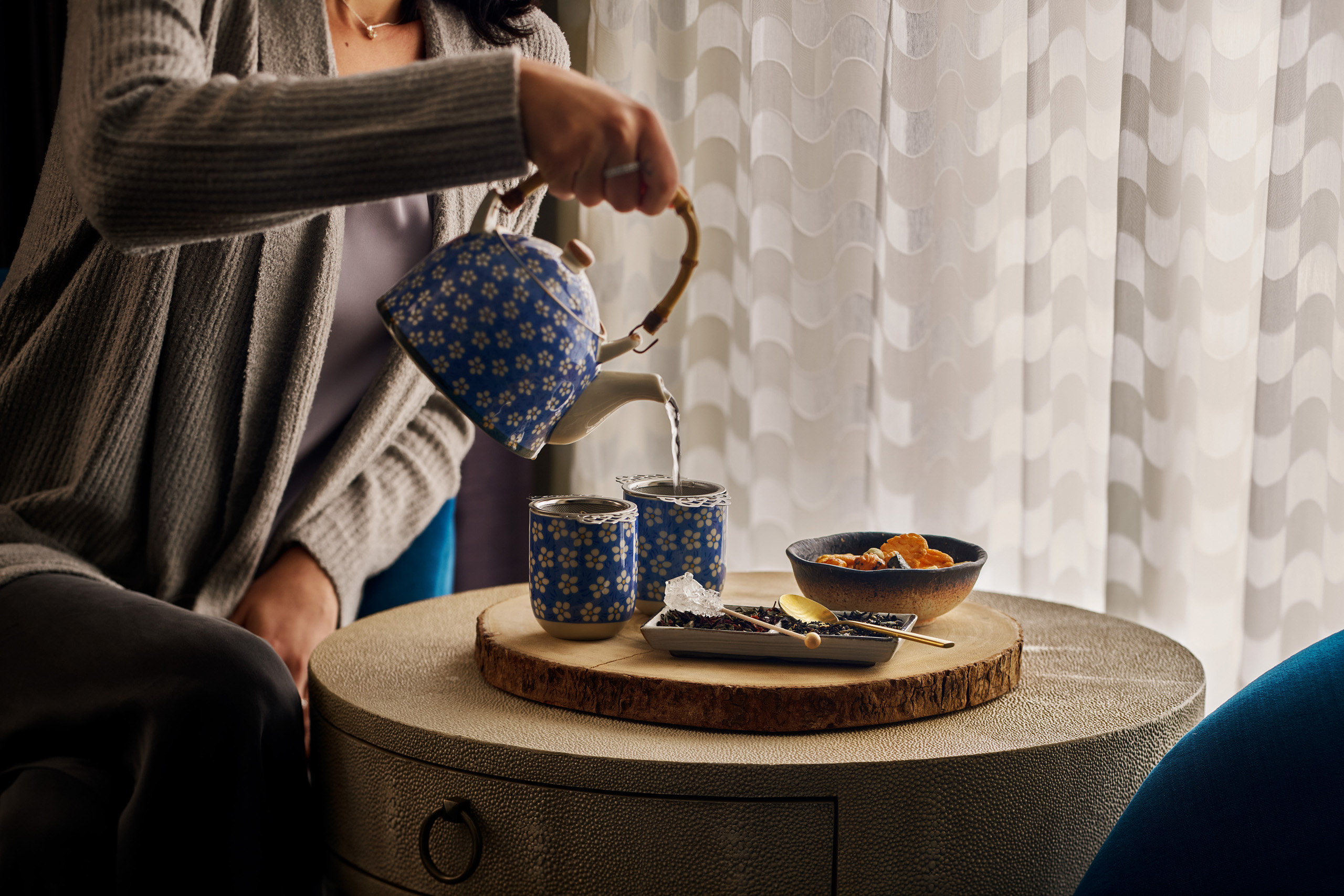 Pouring tea into patterned ceramic cups.