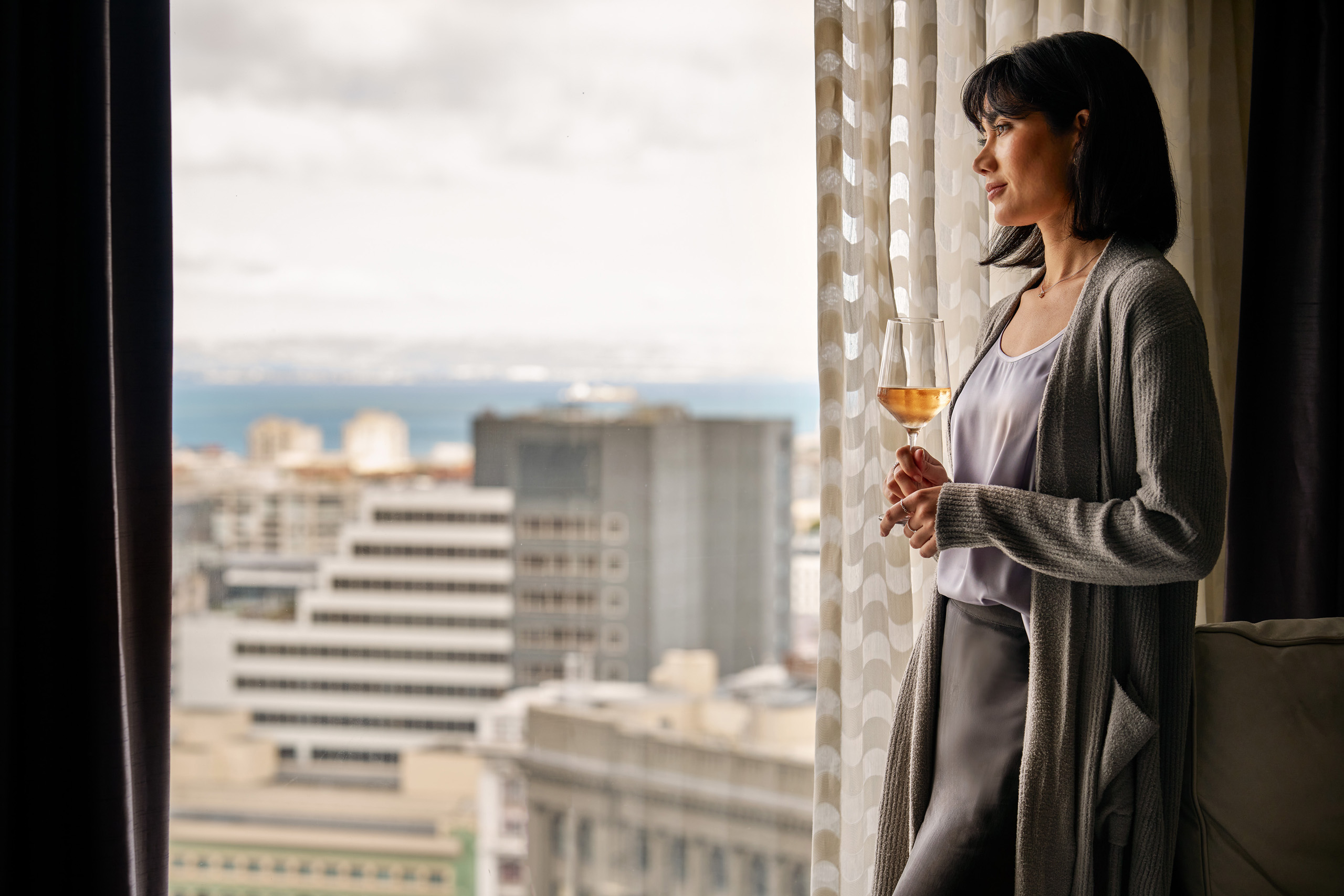 Guest holding wine by hotel window.