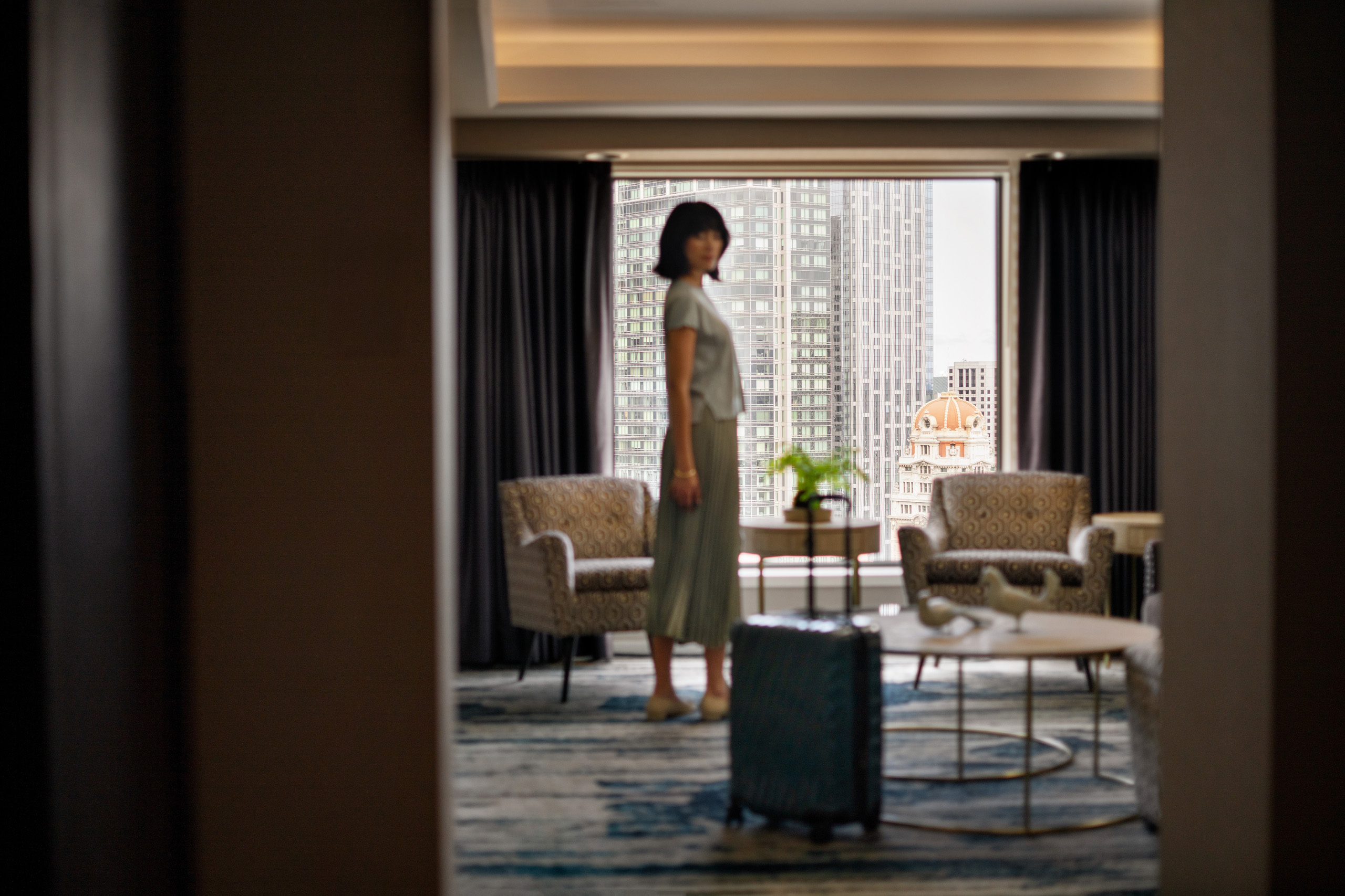 Guest standing in hotel suite with city view.