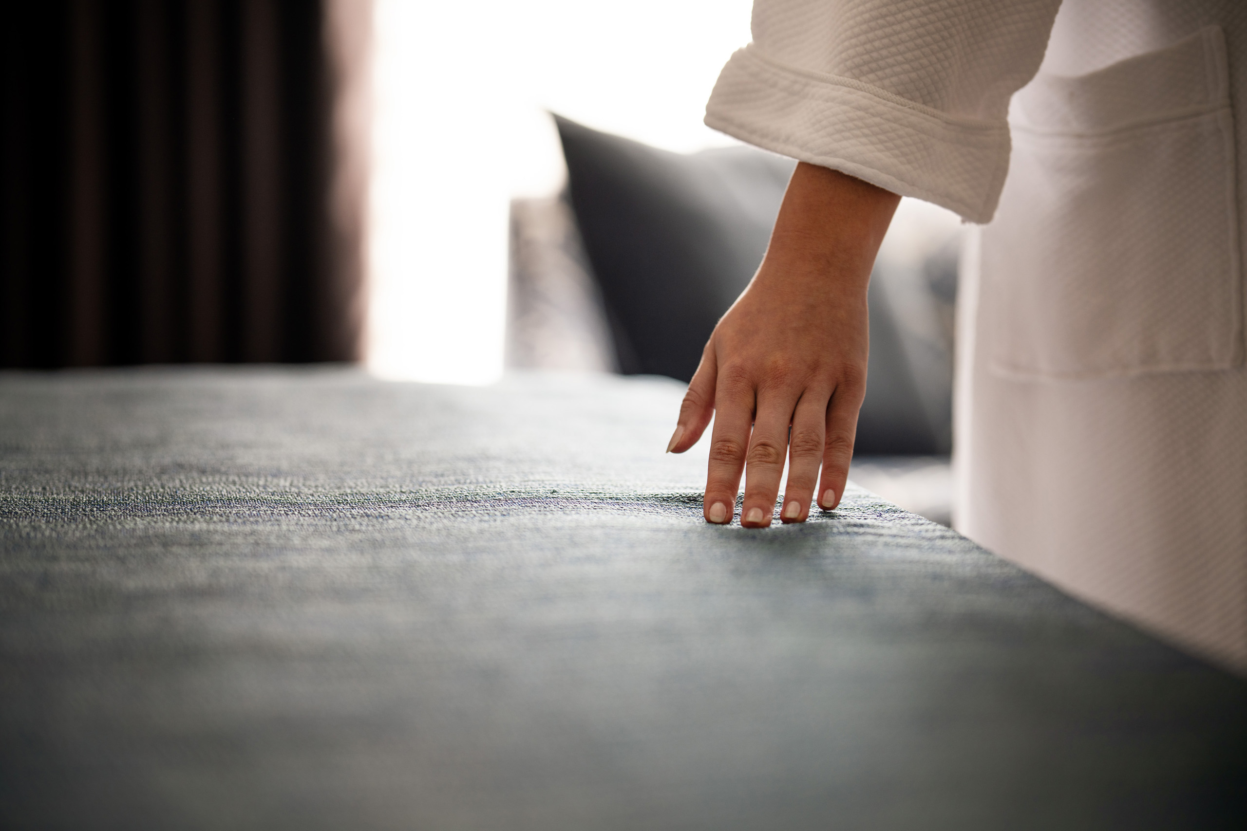 Hand touching neatly made hotel bed