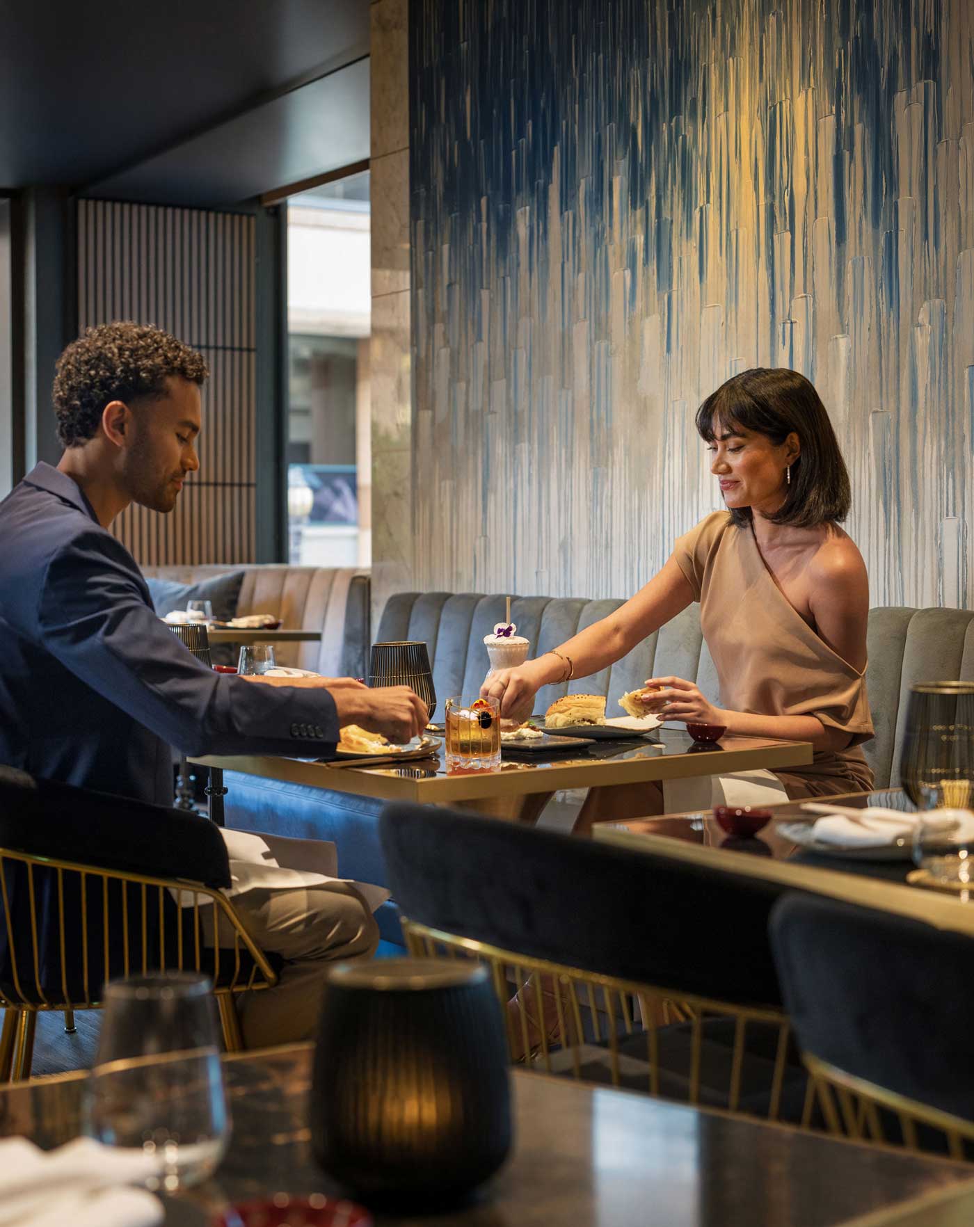 Man and woman having a meal together in a modern restaurant with decorative wallpaper.