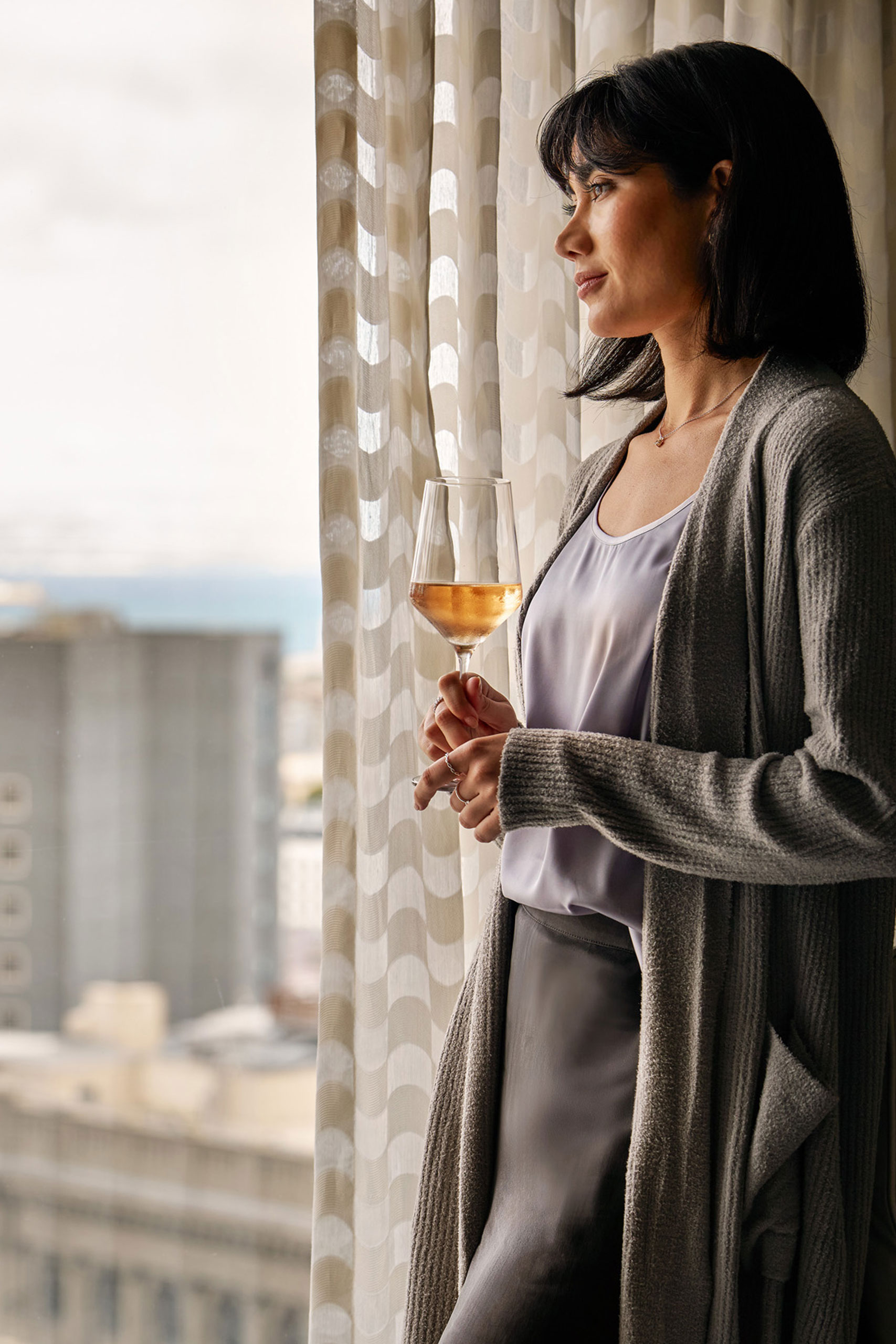 Guest holding wine by hotel window.