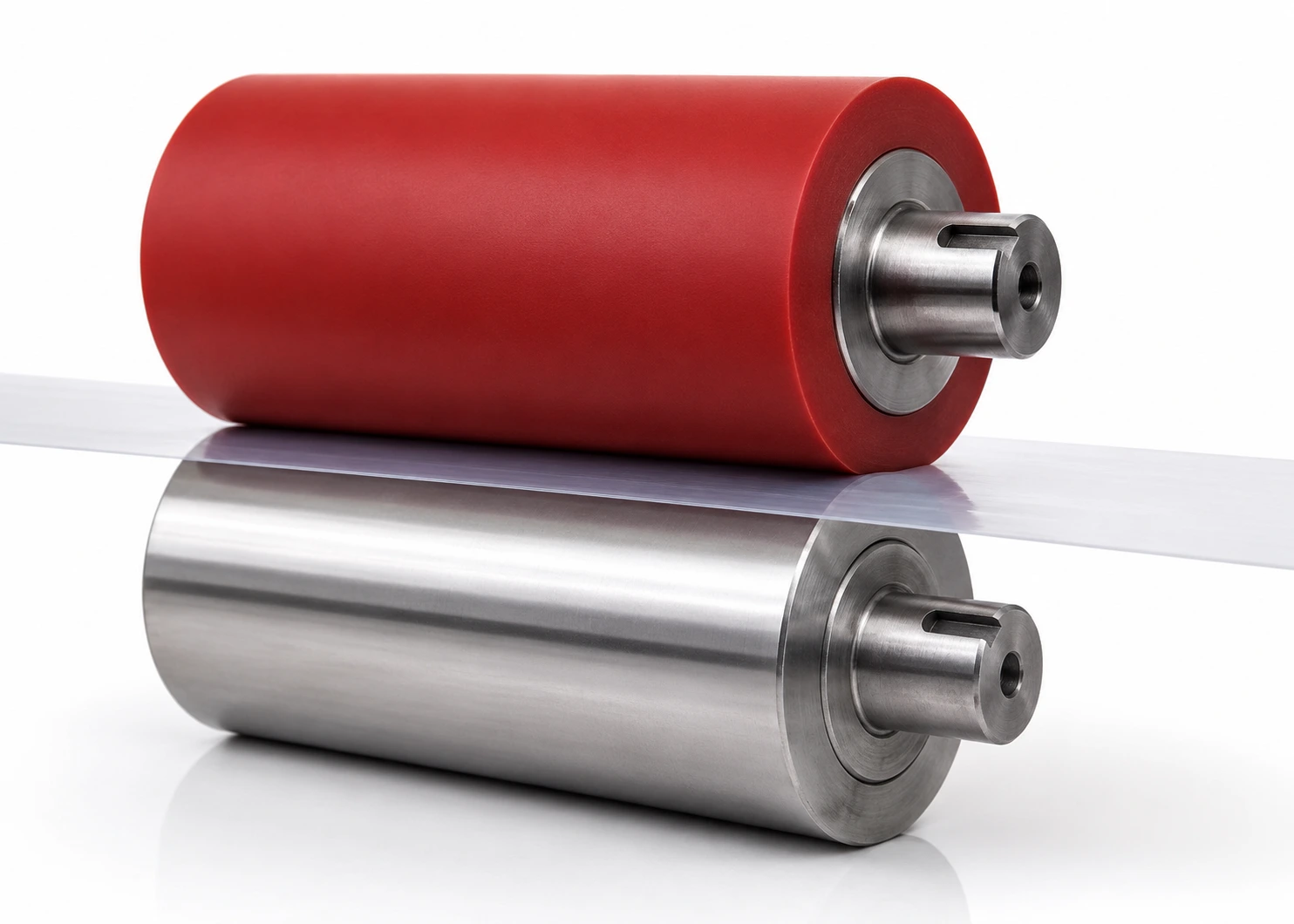 Paire de rouleaux formant un nip — polyuréthane coulé rouge contre acier poli, film plastique pincé sur la ligne de contact