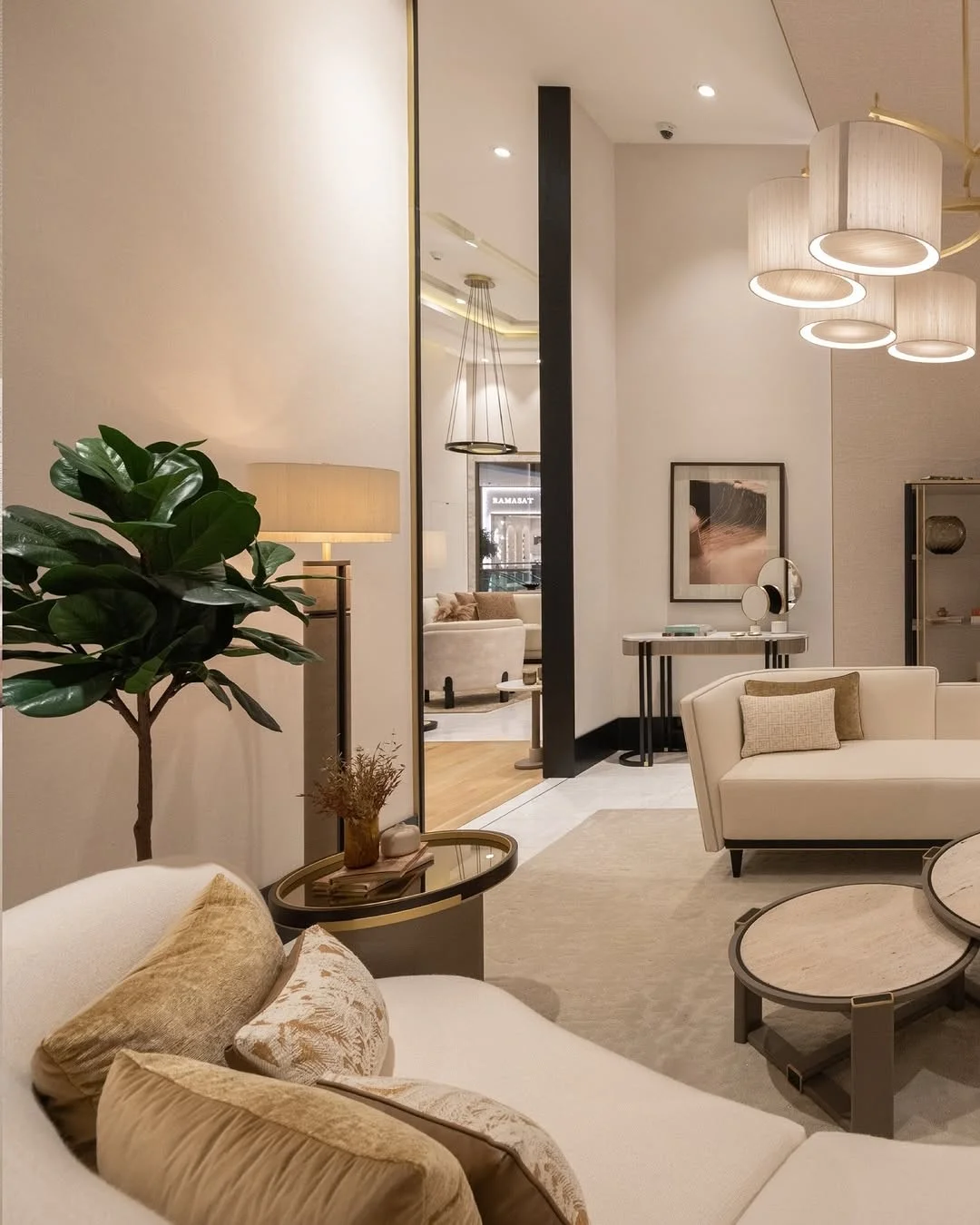 A cream boutique fitting area with soft chairs, mirrors and plants