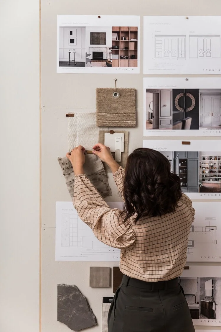An interior designer pinning samples to a mood board on the studio wall