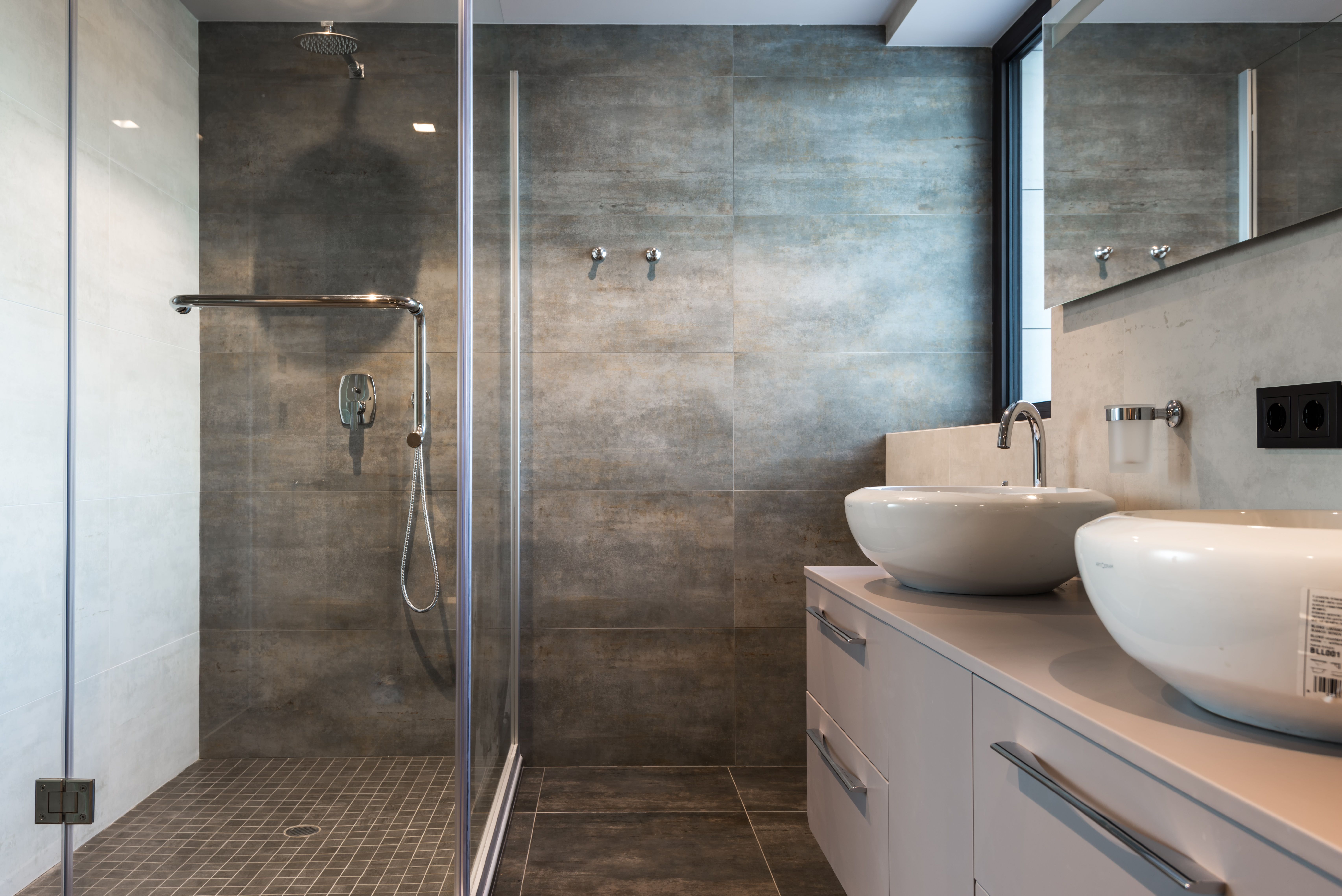 Walk-in glass shower remodel with dual vessel sinks by Coastal Builders Associates