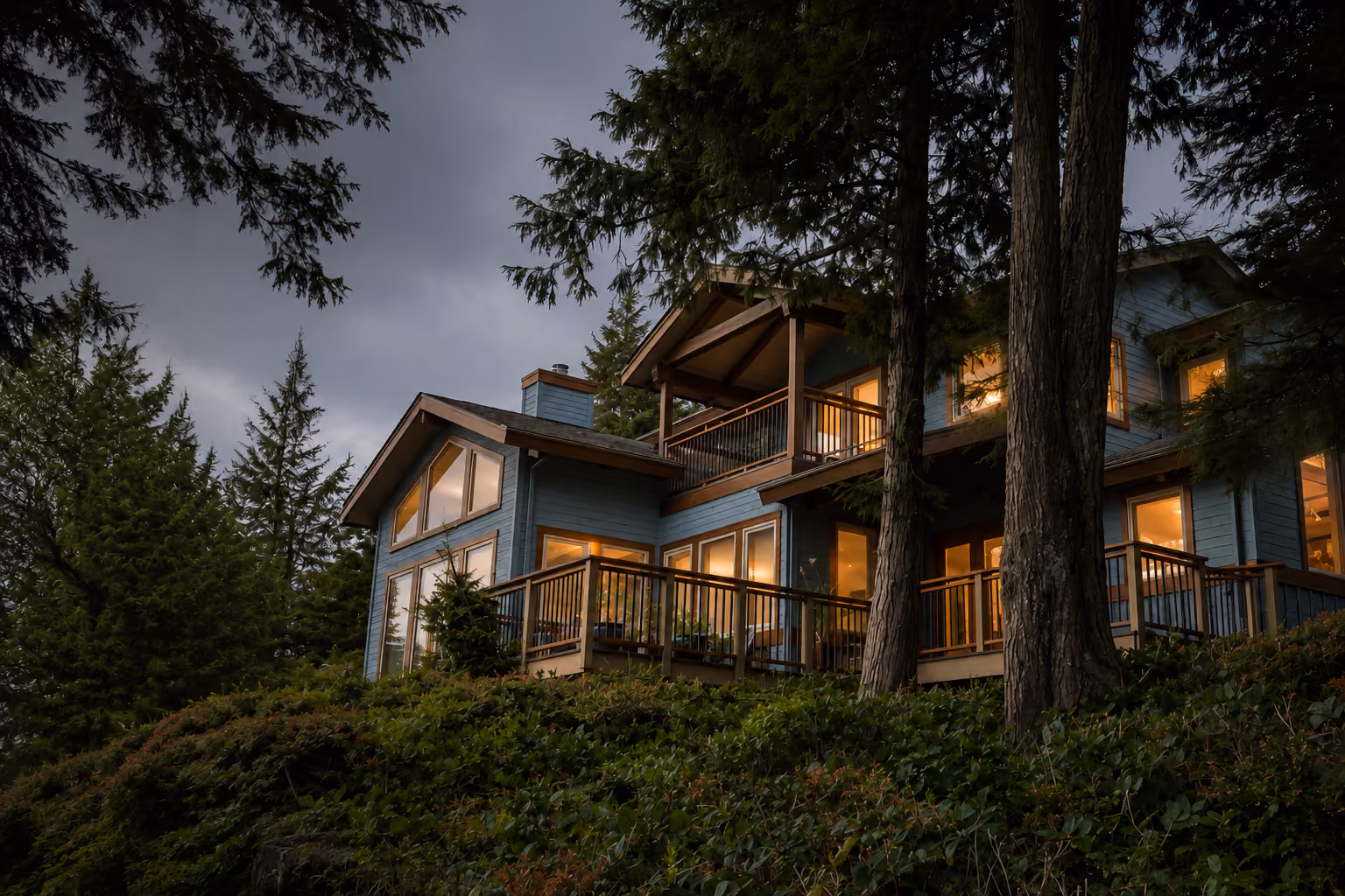 Rainstone Developments west coast style custom home at twilight, nestled in the trees