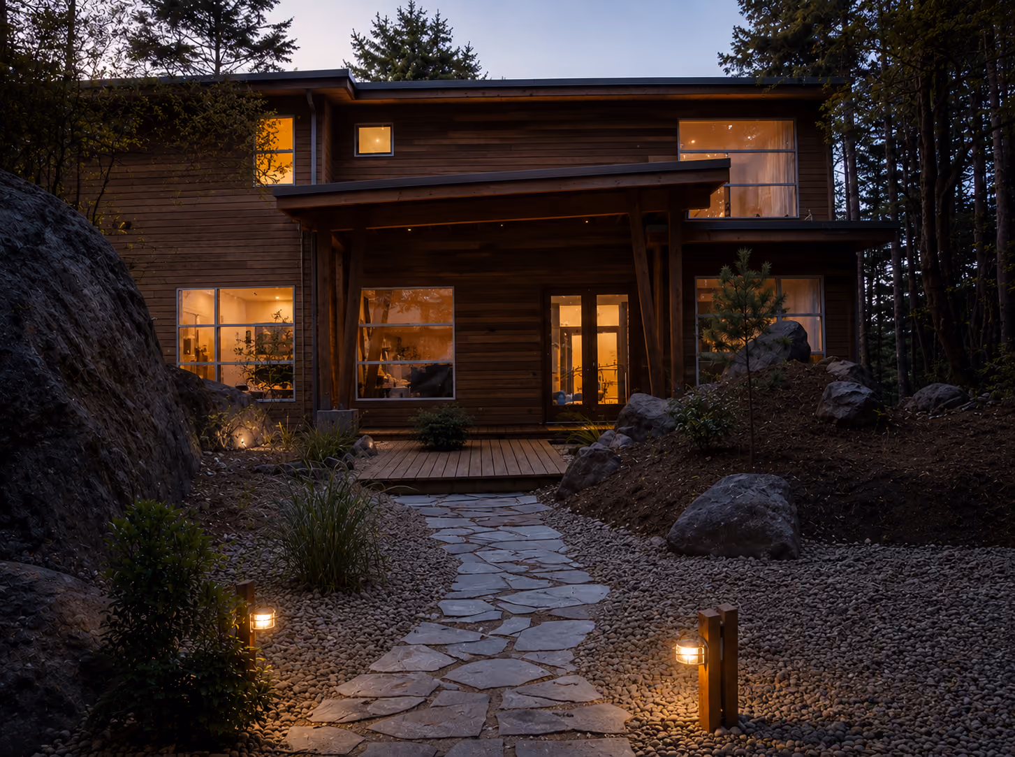 Rainstone Developments modern custom home at twilight in west coast style with natural textures of wood and stone and large windows