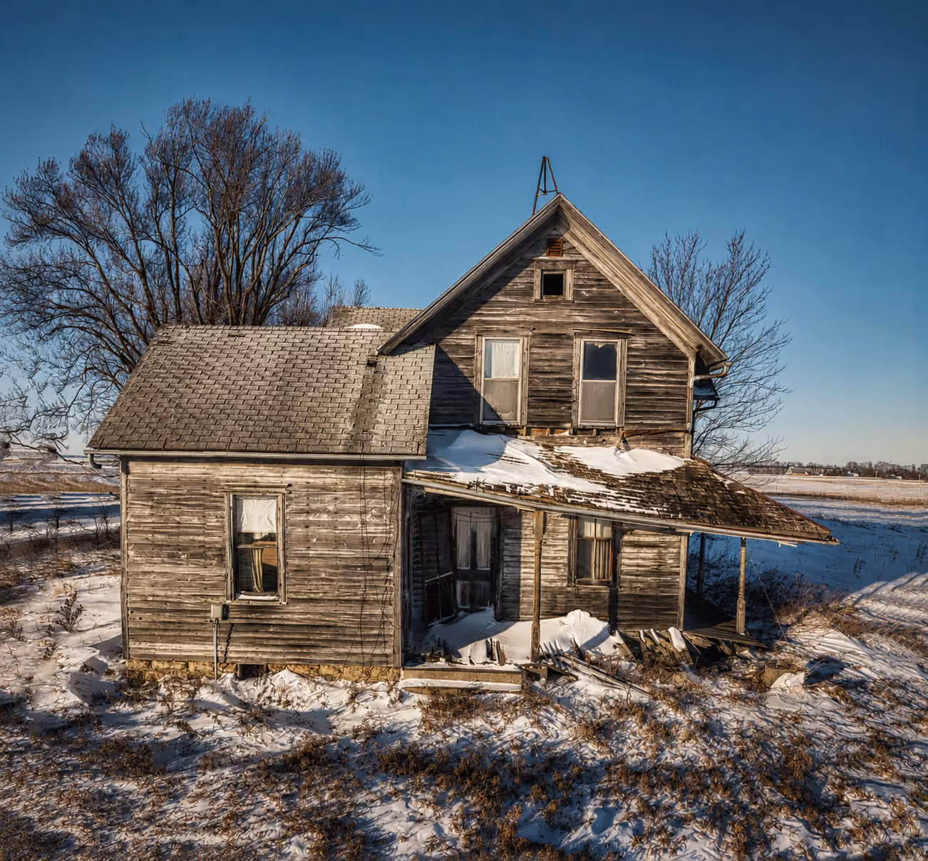 dilapidated abandoned home with weathered grey wood and leaning porch